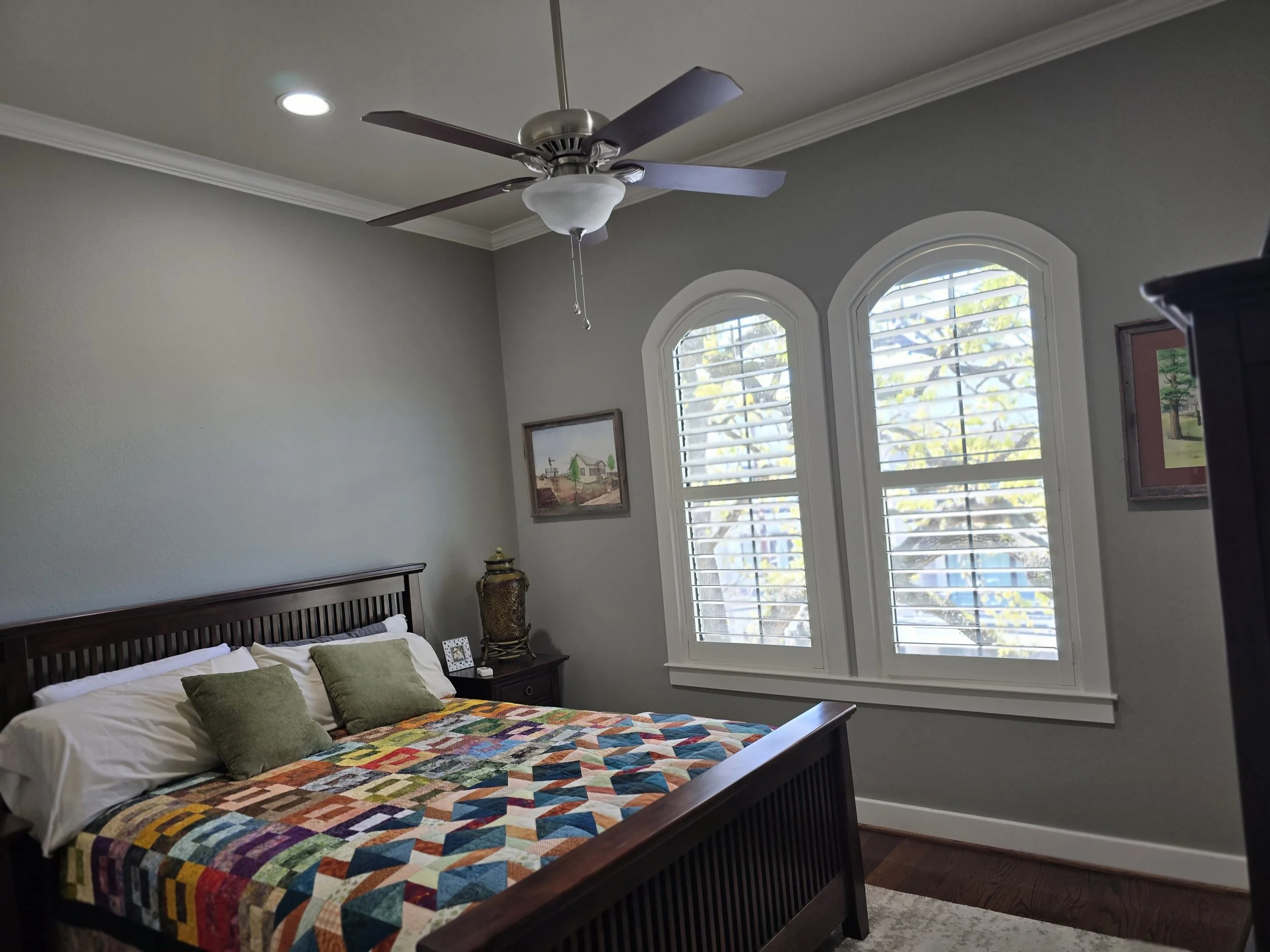 Bedroom interior painting in Fulshear TX featuring soft gray walls, white crown molding, and custom window trim