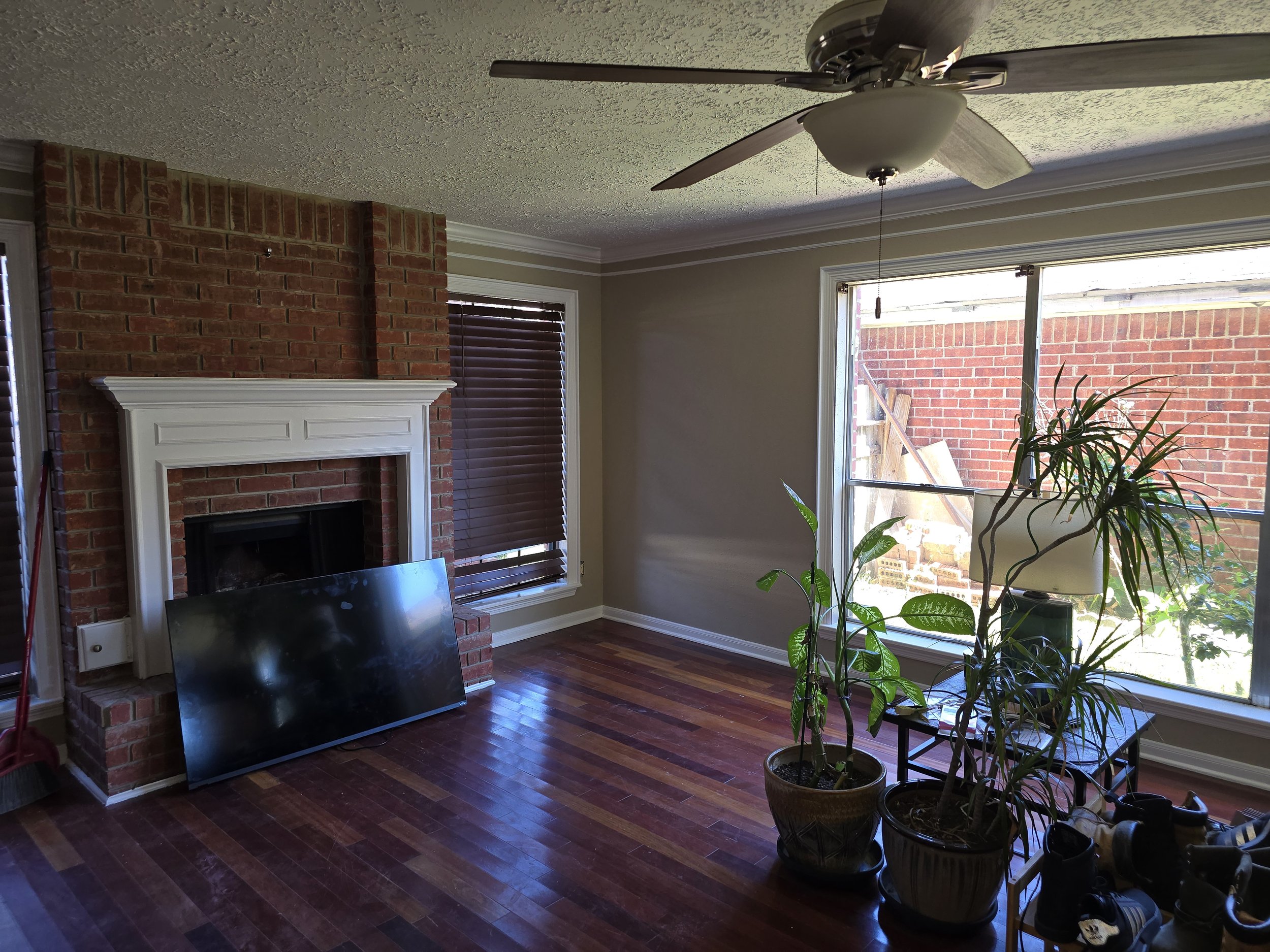 Freshly painted living room with hardwood floors and brick fireplace in Missouri City, TX interior painting project by The Proud Paintbrush.