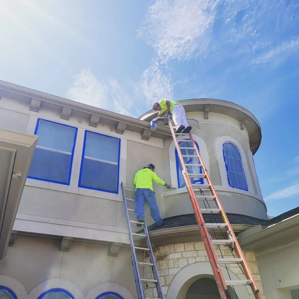 Two professional painters preparing a house exterior for painting in Sugar Land, Texas.