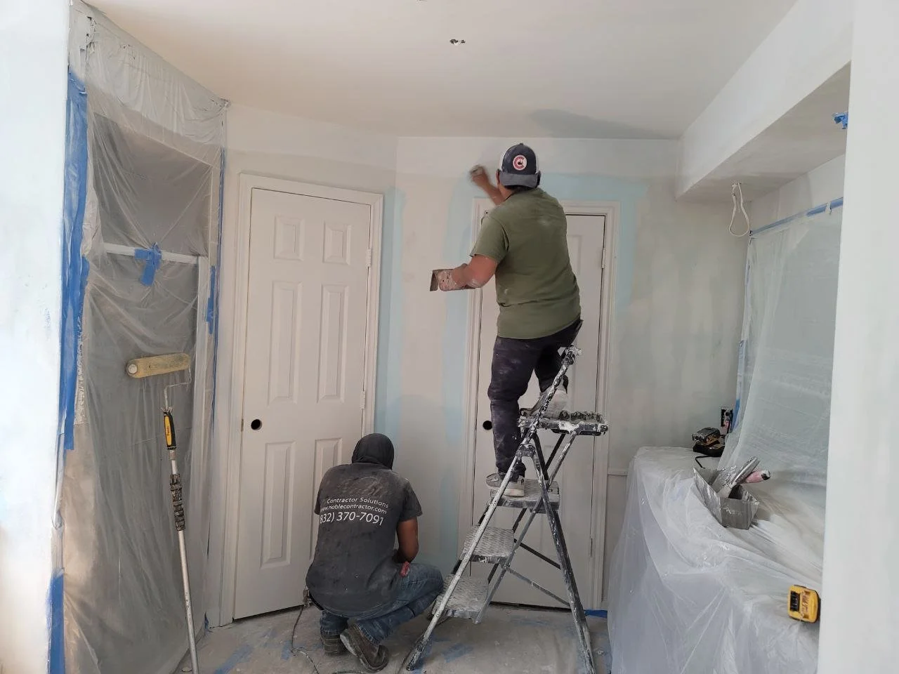 Two professional painters working in a bathroom with surfaces masked and protected during painting in Richmond, Texas
