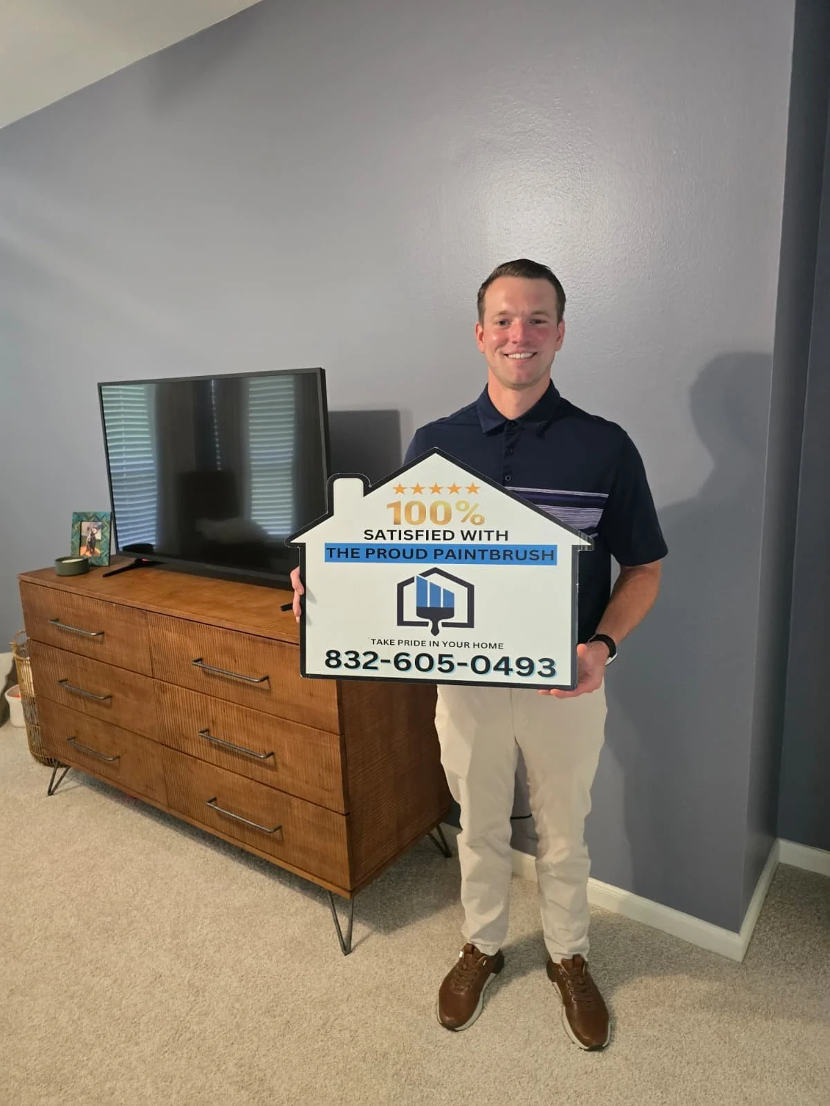 happy customer holding a sign 100% satisfied with interior paint job