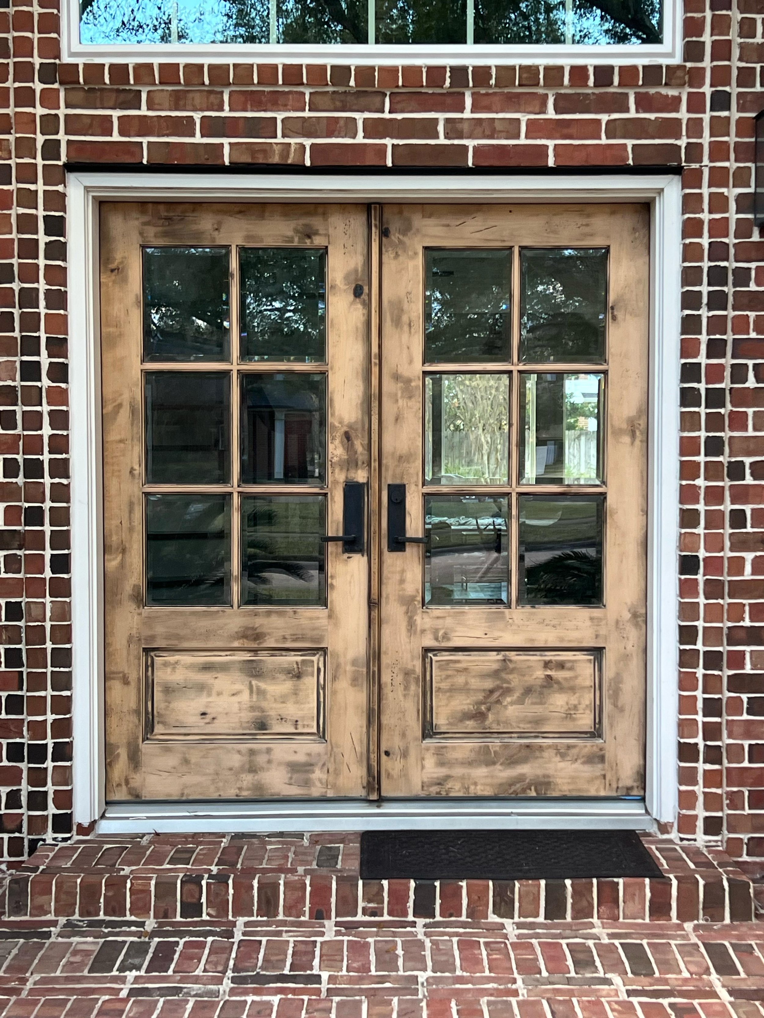 Before photo of front door refinishing project at a Rosenberg home showing worn wood doors