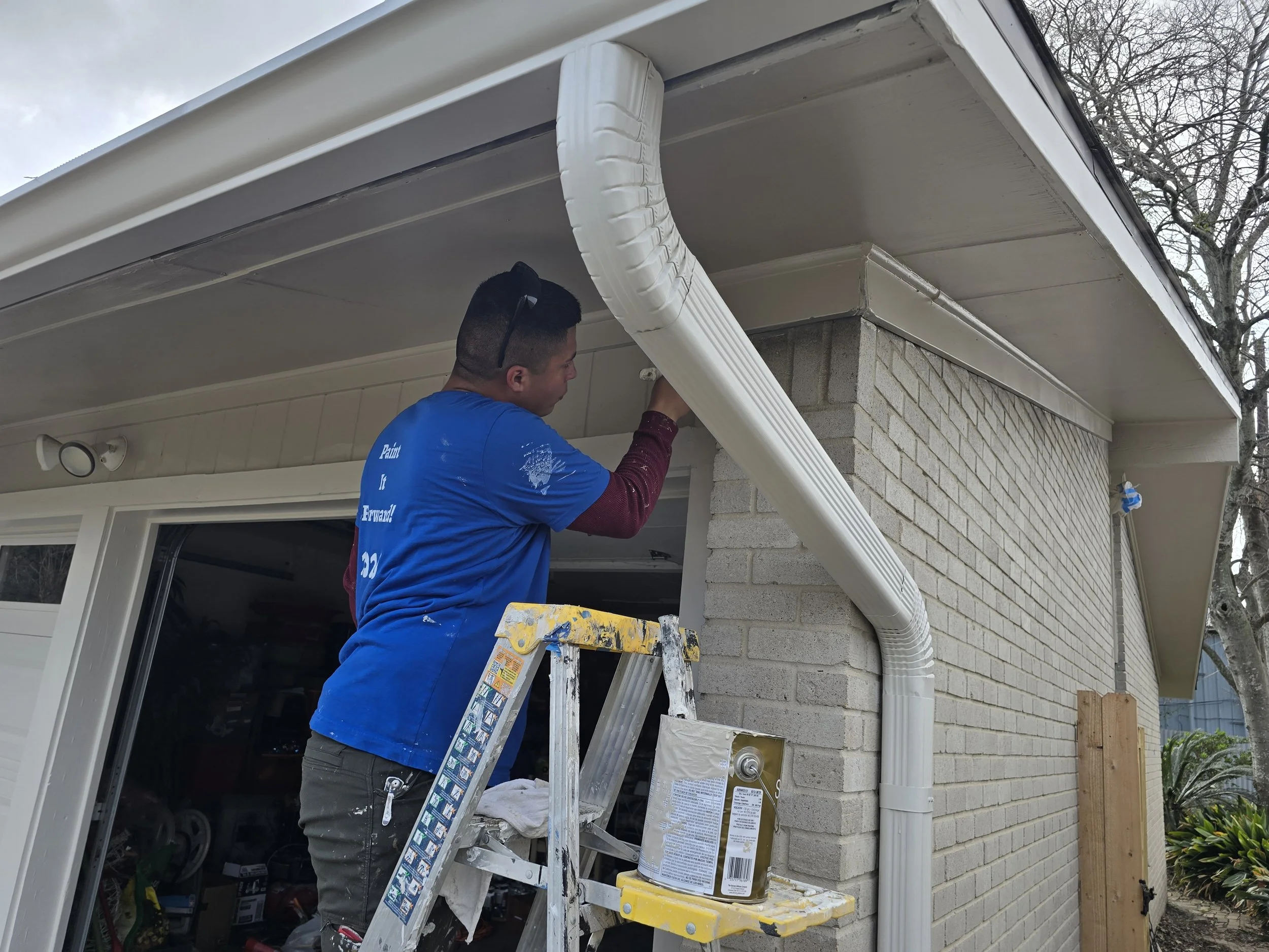 Professional painter brushing soffit and performing touch-ups during Paint It Forward 2026 in West Houston, Texas.