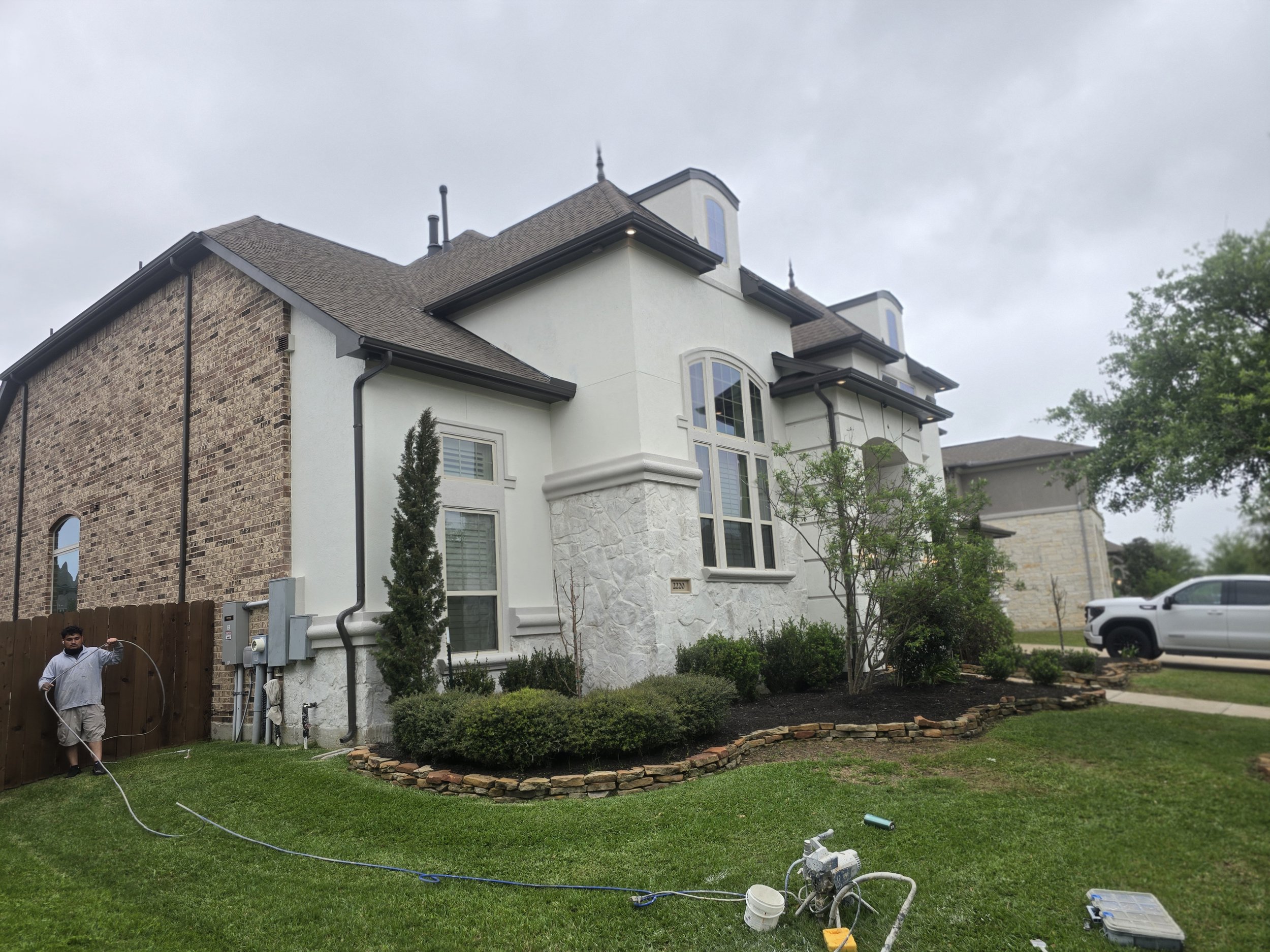 Exterior painting in Fulshear TX with stucco and stone finishes, detailed trim work, and professional spray application