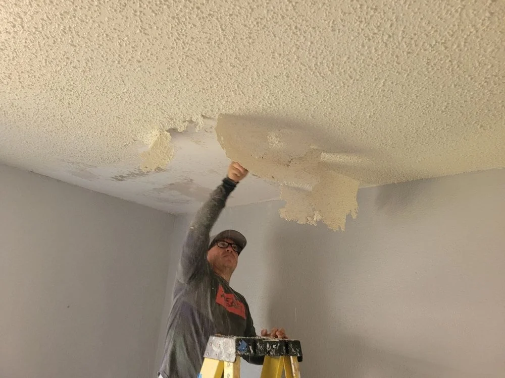 Contractor scraping popcorn texture from a ceiling during popcorn ceiling removal in Southwest Houston, Texas.