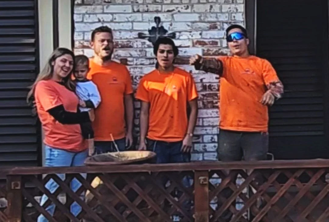 Chris Petkau, owner of The Proud Paintbrush, with his wife, son, and two professional painters in front of a freshly painted home exterior in Sugar Land, Texas