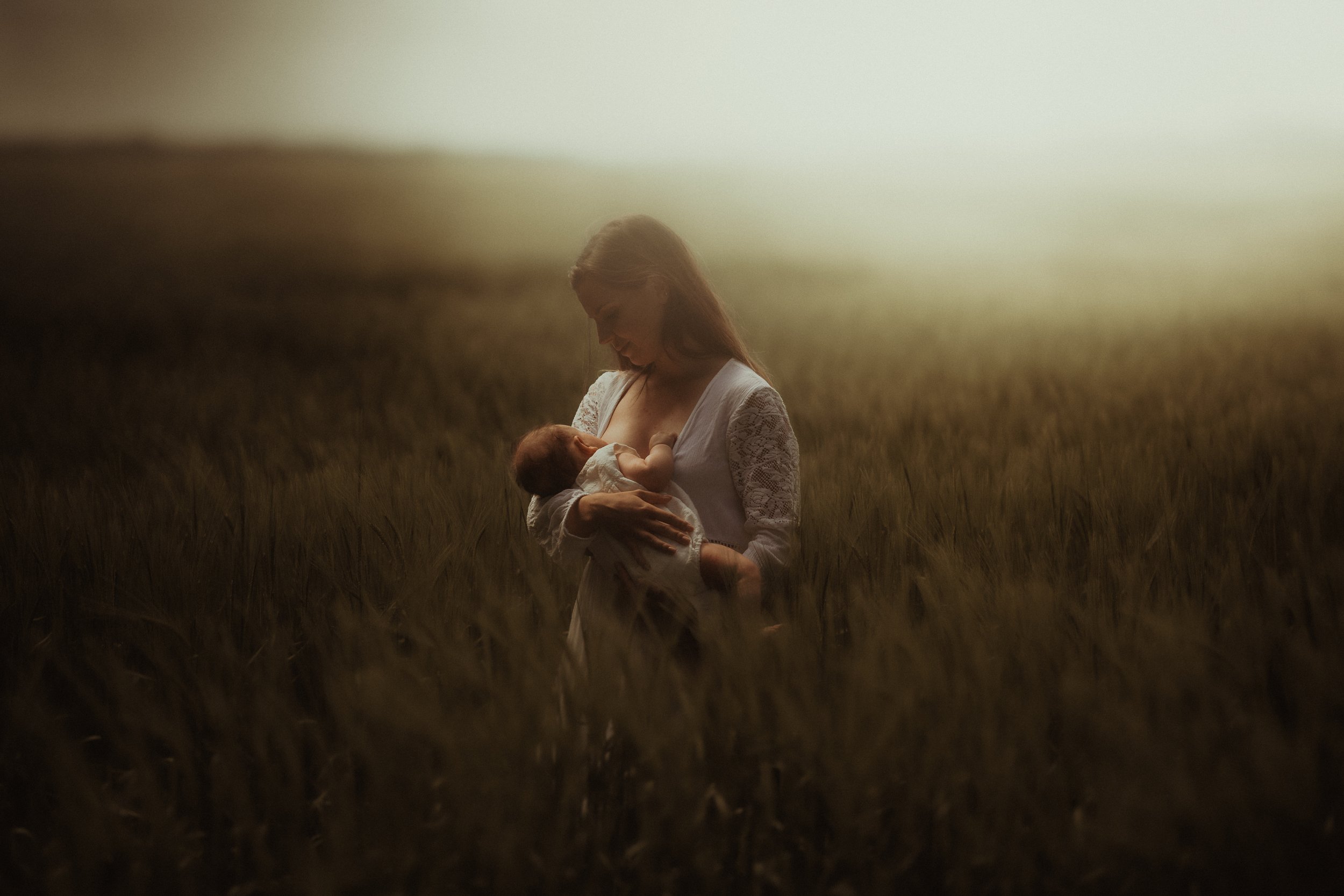 Mother standing in a field, breastfeeding