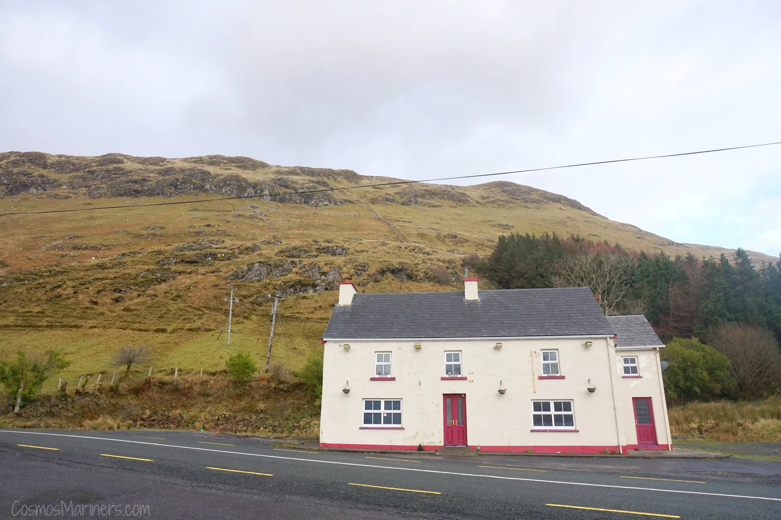 Cute town by the road in Connemara with red doors and mountain behind it