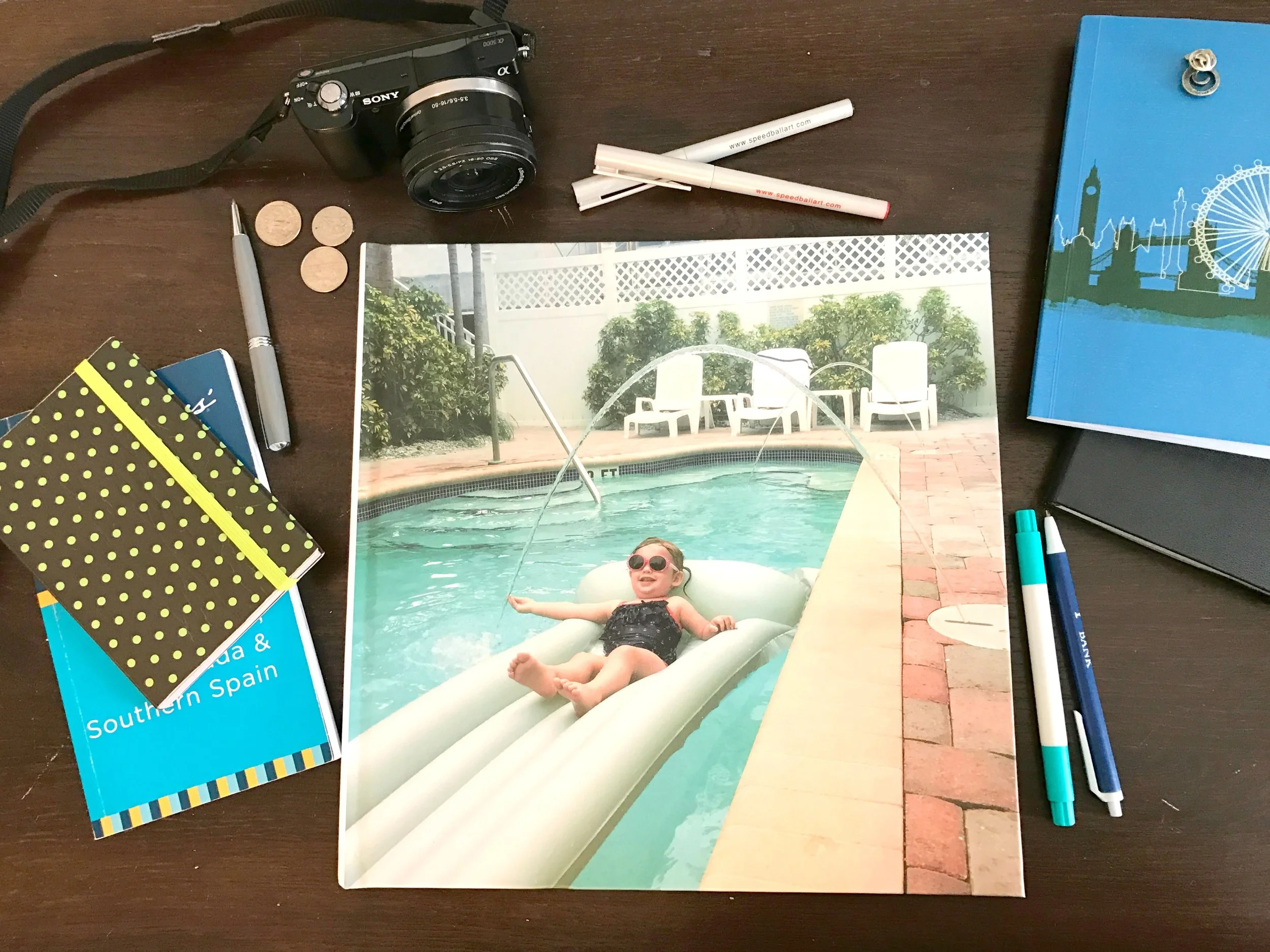 Flatlay of a 12x12 Blurb photo book with a toddler in a pool with sunglasses on