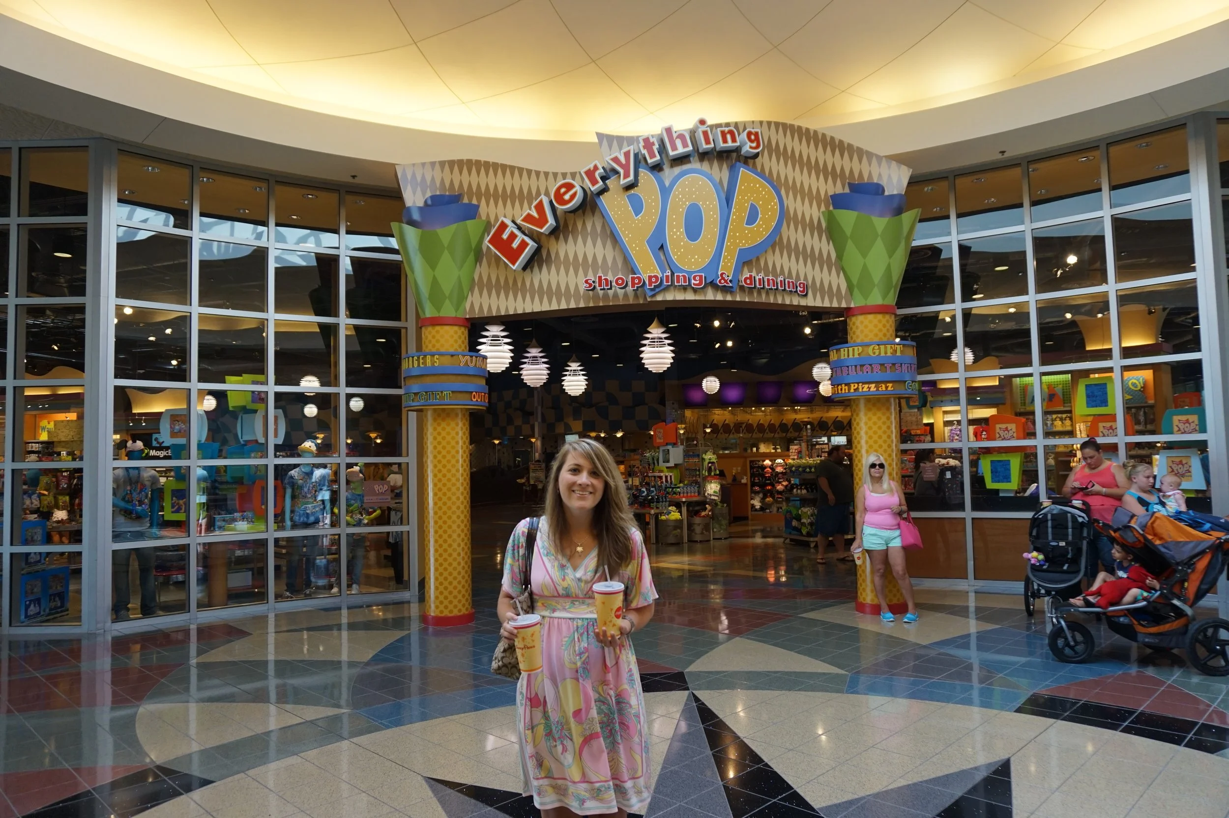 The author's sister wearing a pink dress outside of the Pop Century souvenir shop