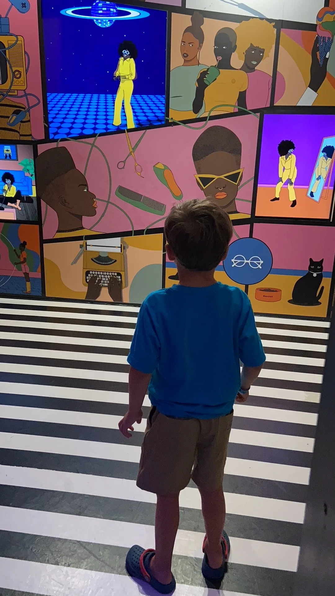 The author's son standing in front of a disco themed room in Meow Wolf