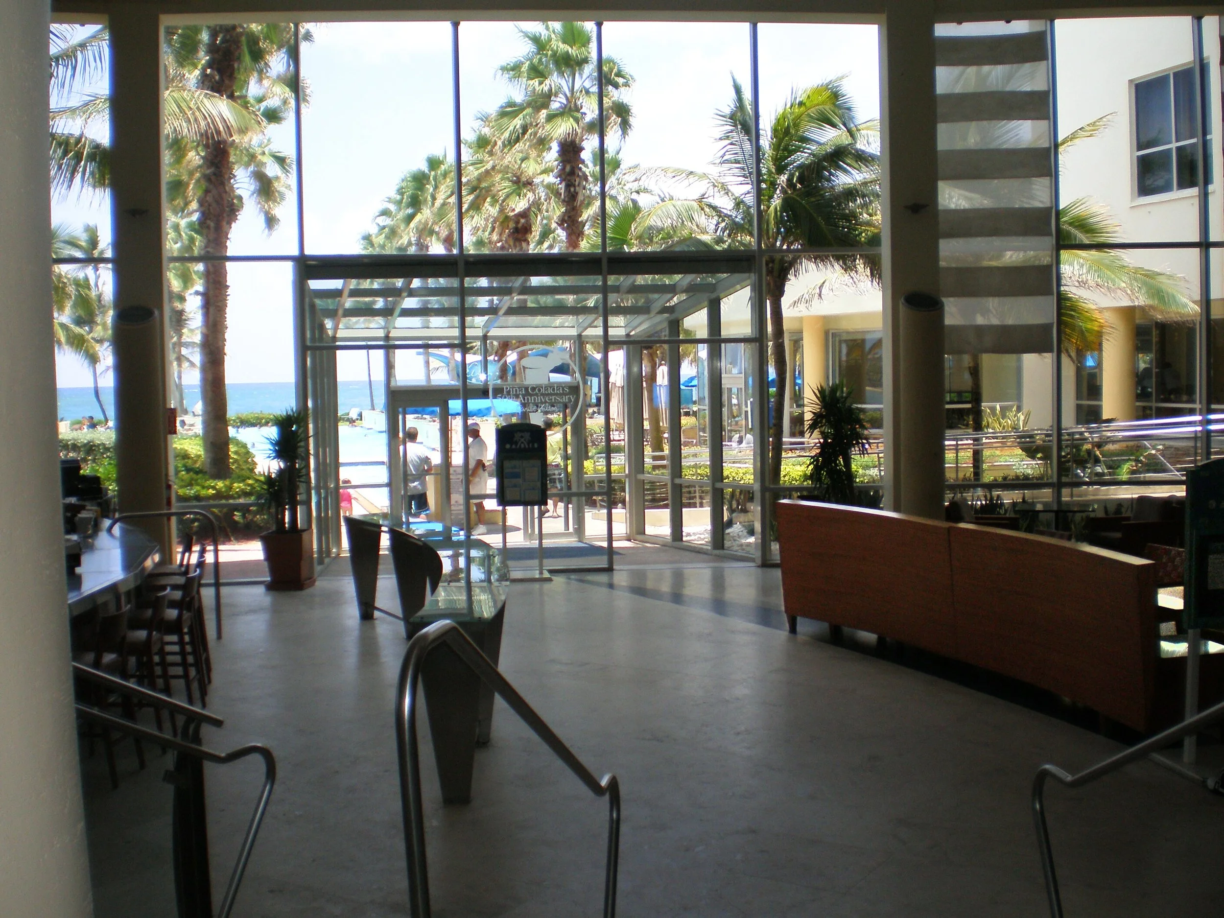 In the Caribe Hilton lobby with a seating area to the right, bar to the left and pool directly ahead