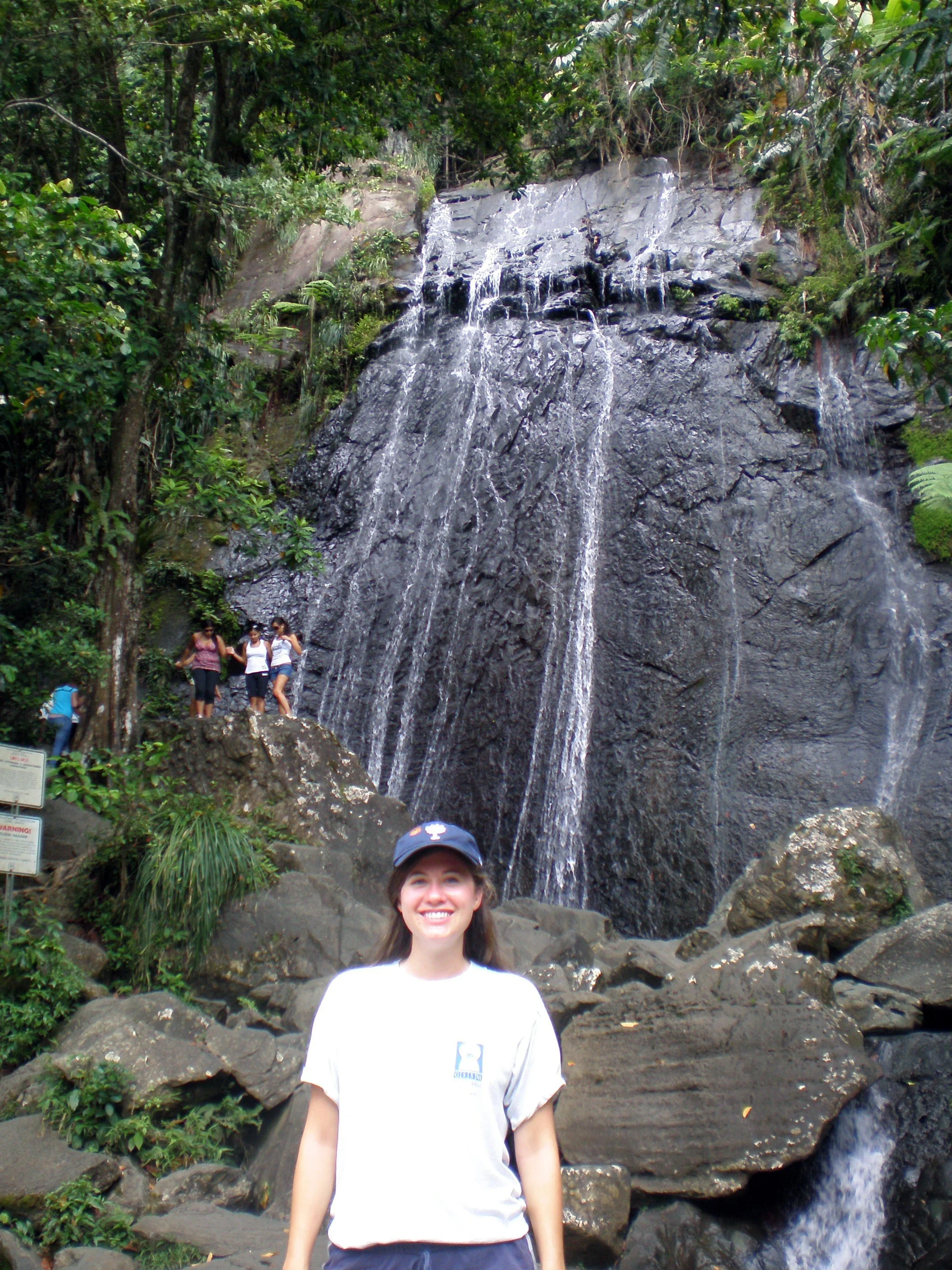 The author in a grey t-shirt and blue baseball hat standing in front of La Coca Falls in El Yunque National Forest