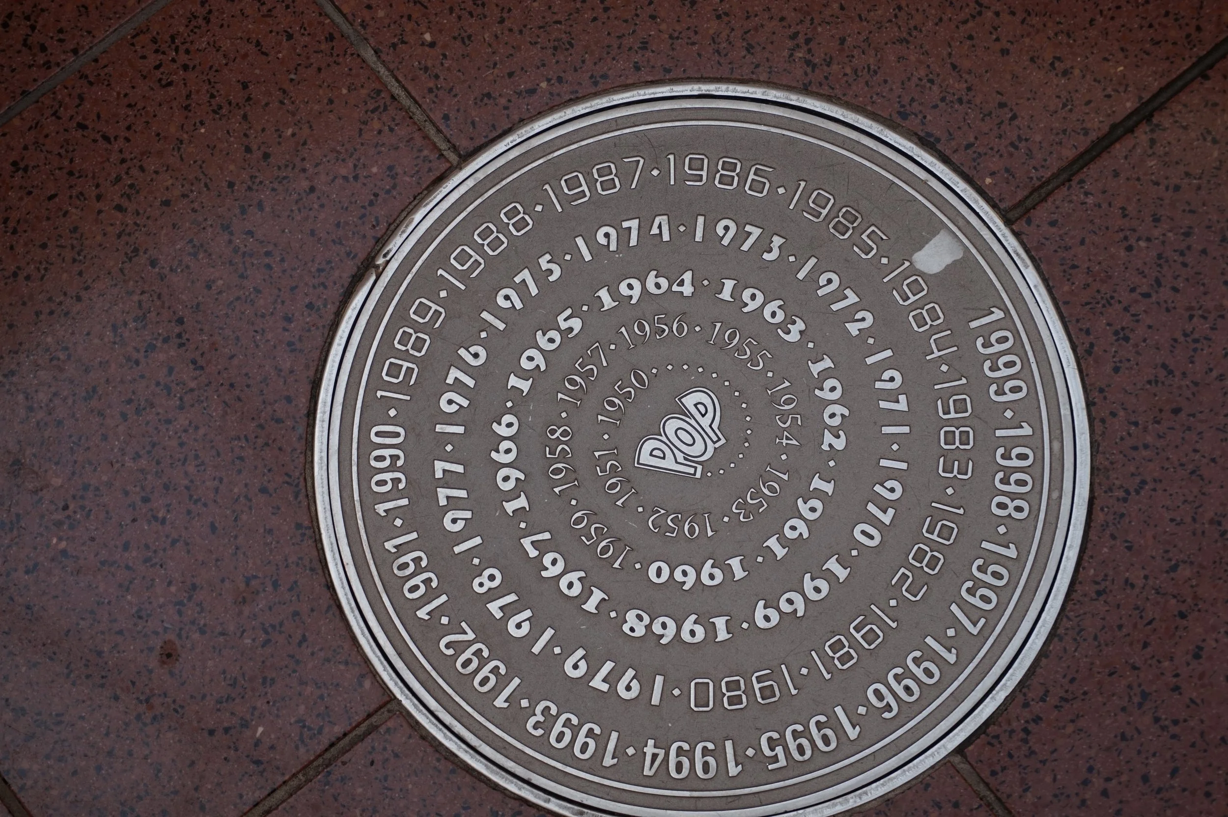 The man hole covers at Pop Century have decades of the 20th century written in a spiral