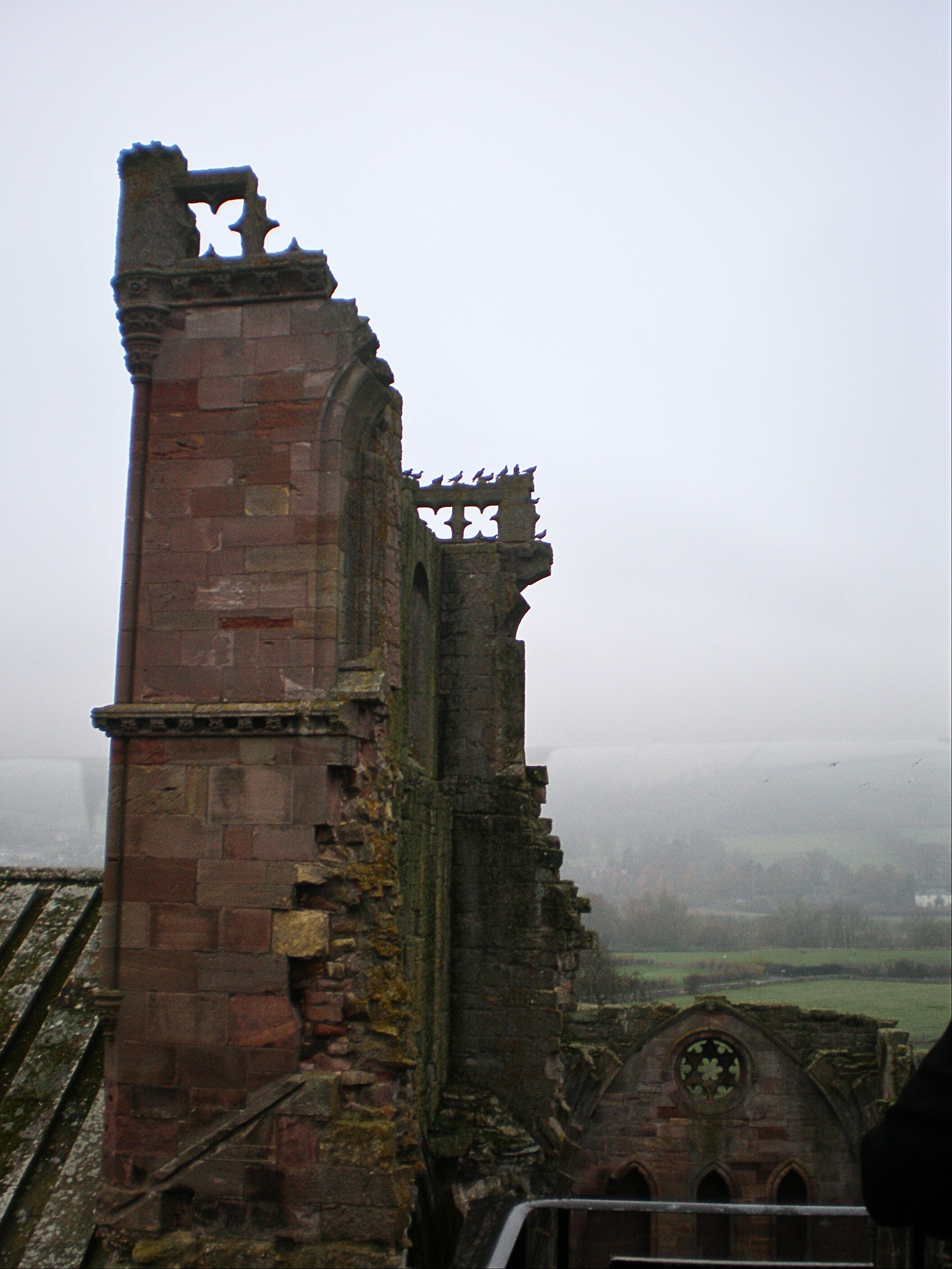 Top of the former bell tower at Melrose Abbey with a foggy forest in the background