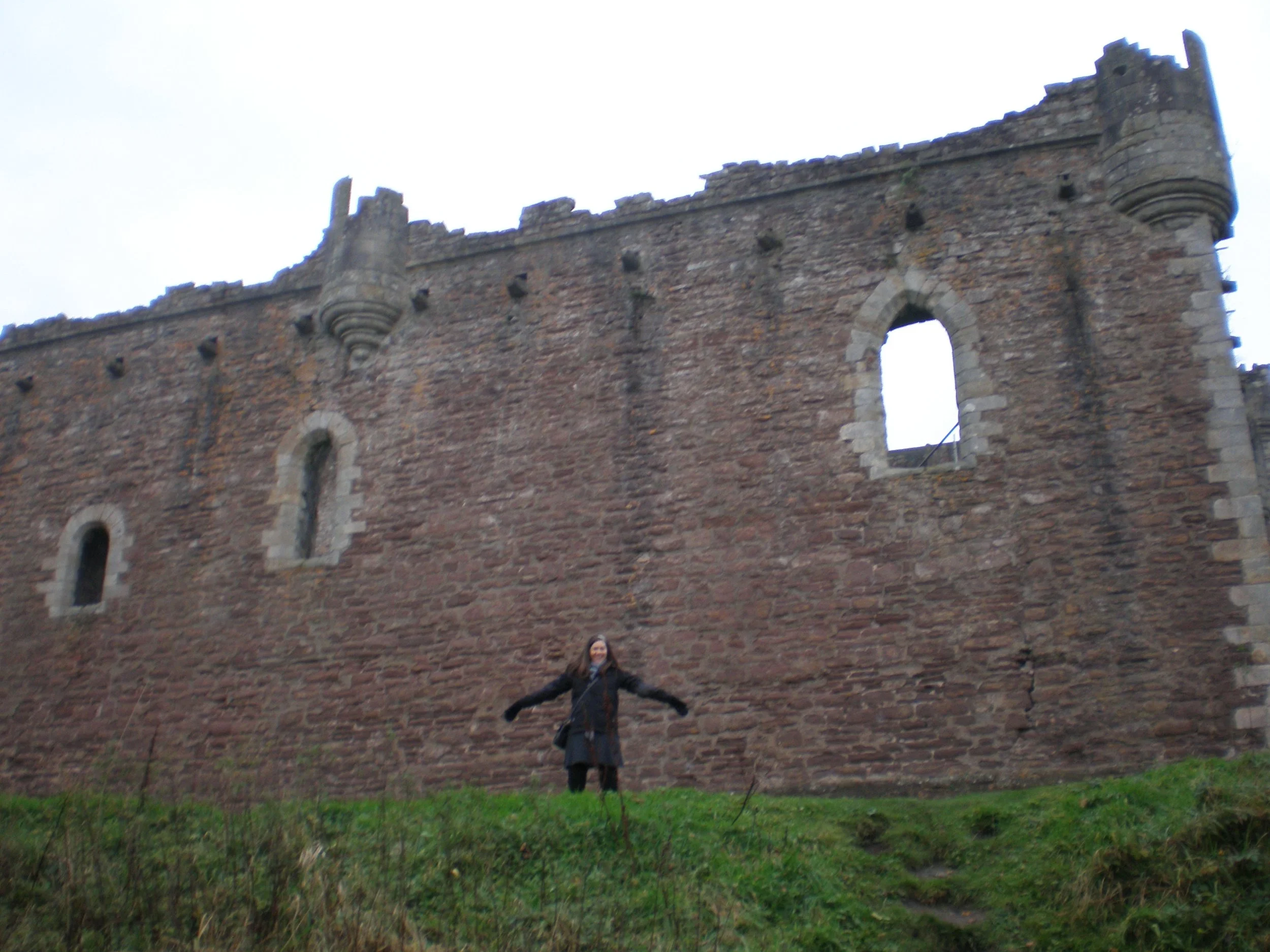 The author standing in front of Doune Castle with her arms outstretched