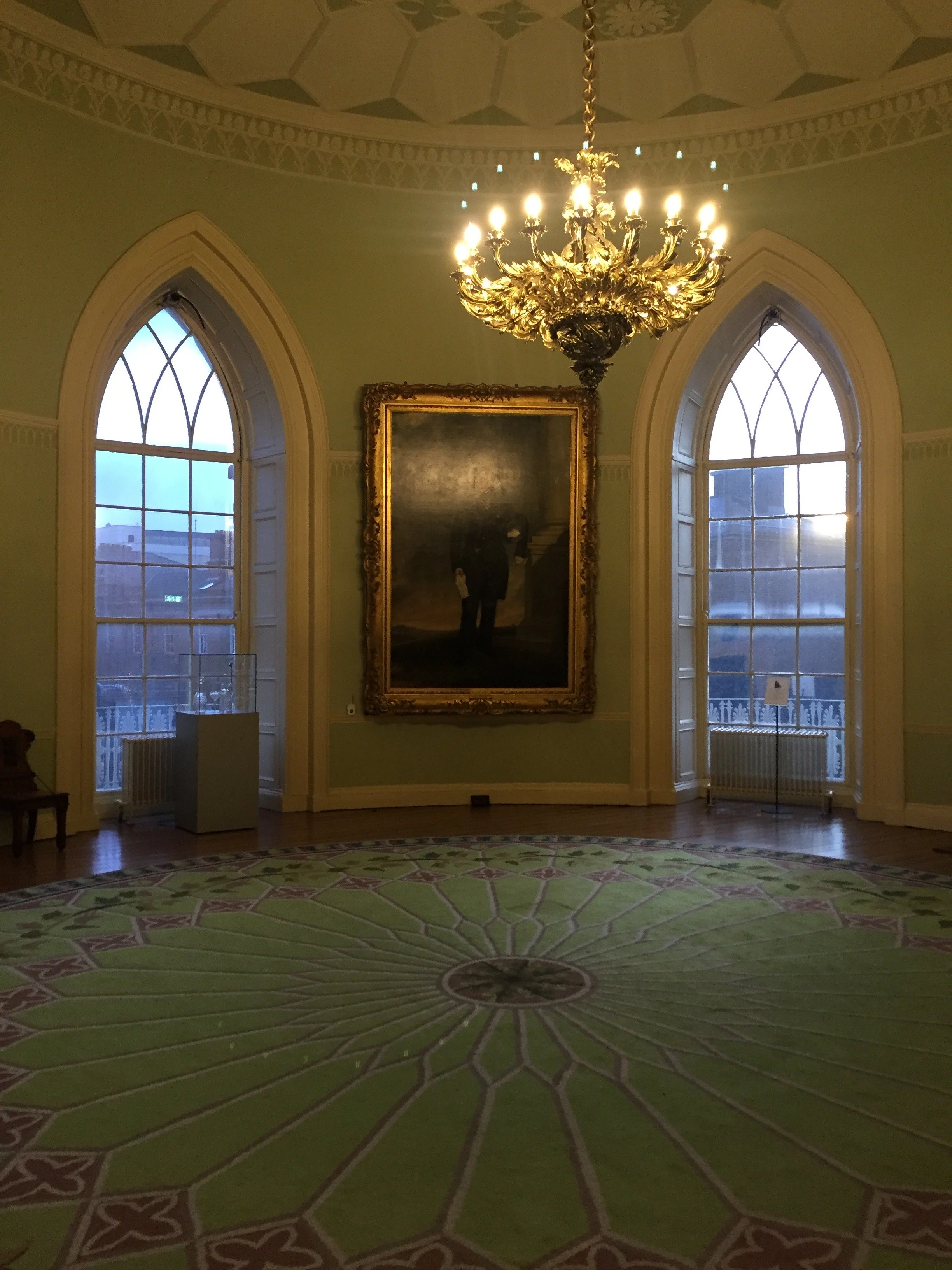 Chandelier, green rug and portrait inside circular room at Dublin Castle