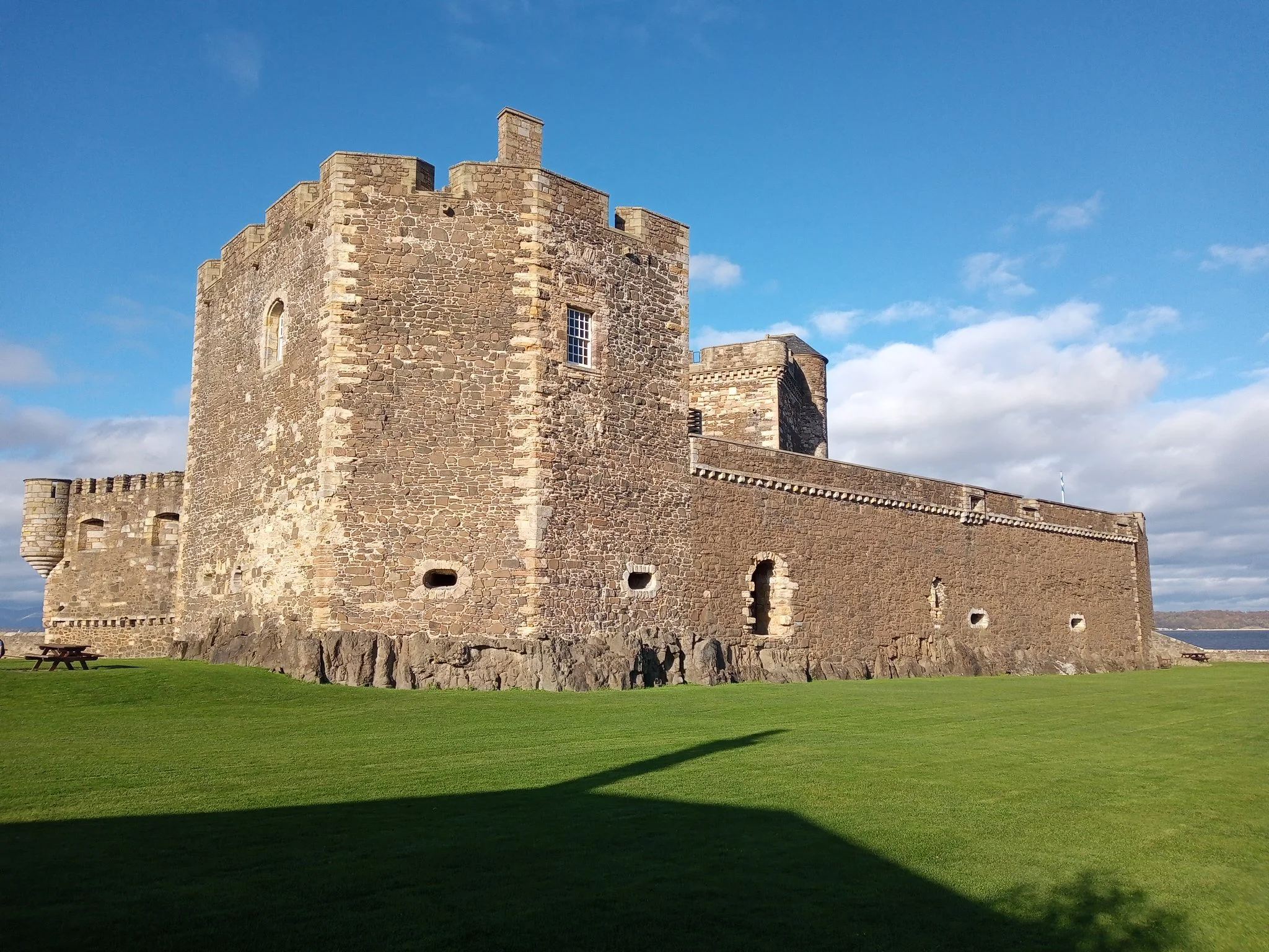 The stone facade of Blackness Castle with green lawn and blue sky