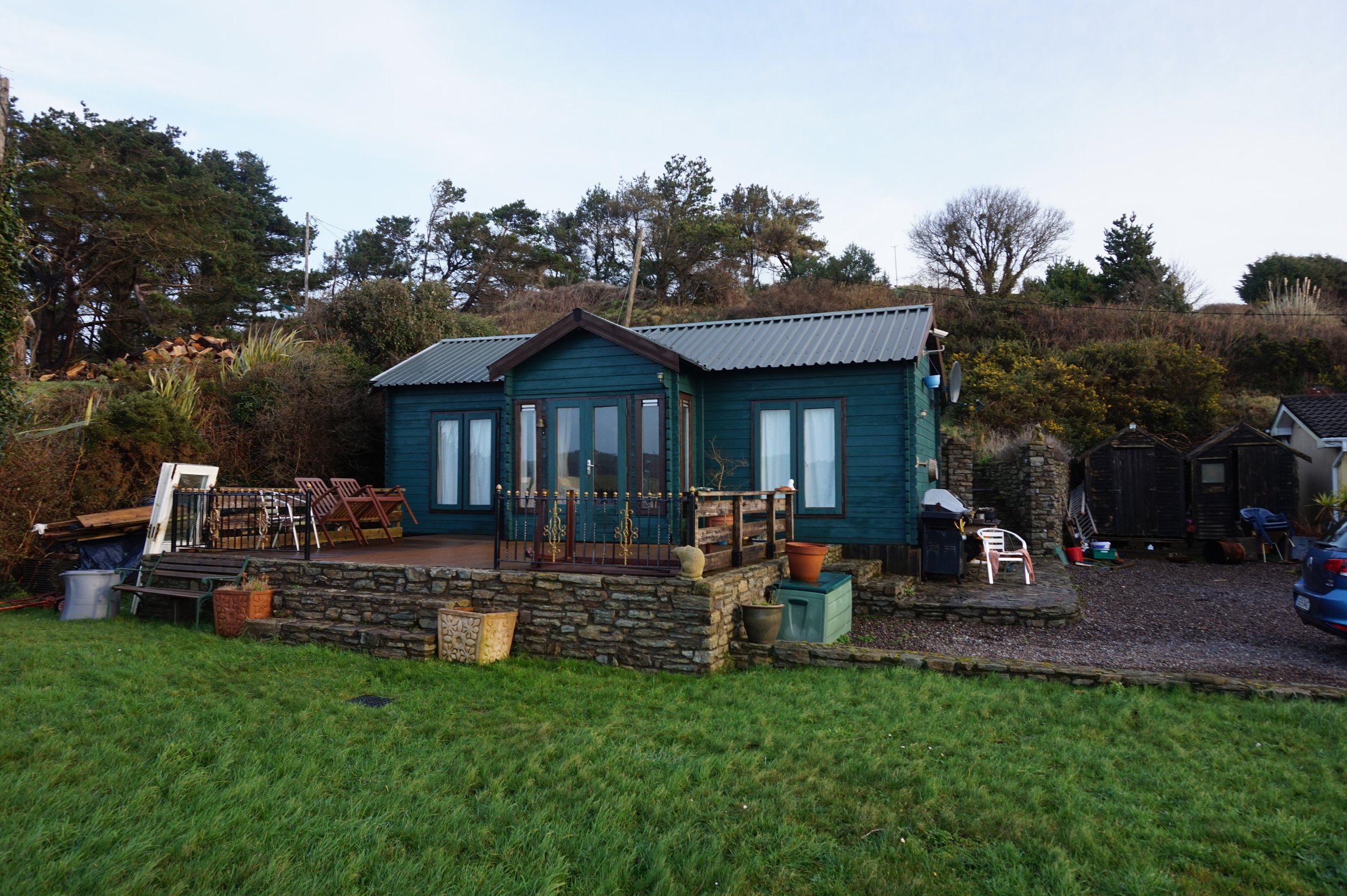 Small aqua blue cottage with a stone porch out front