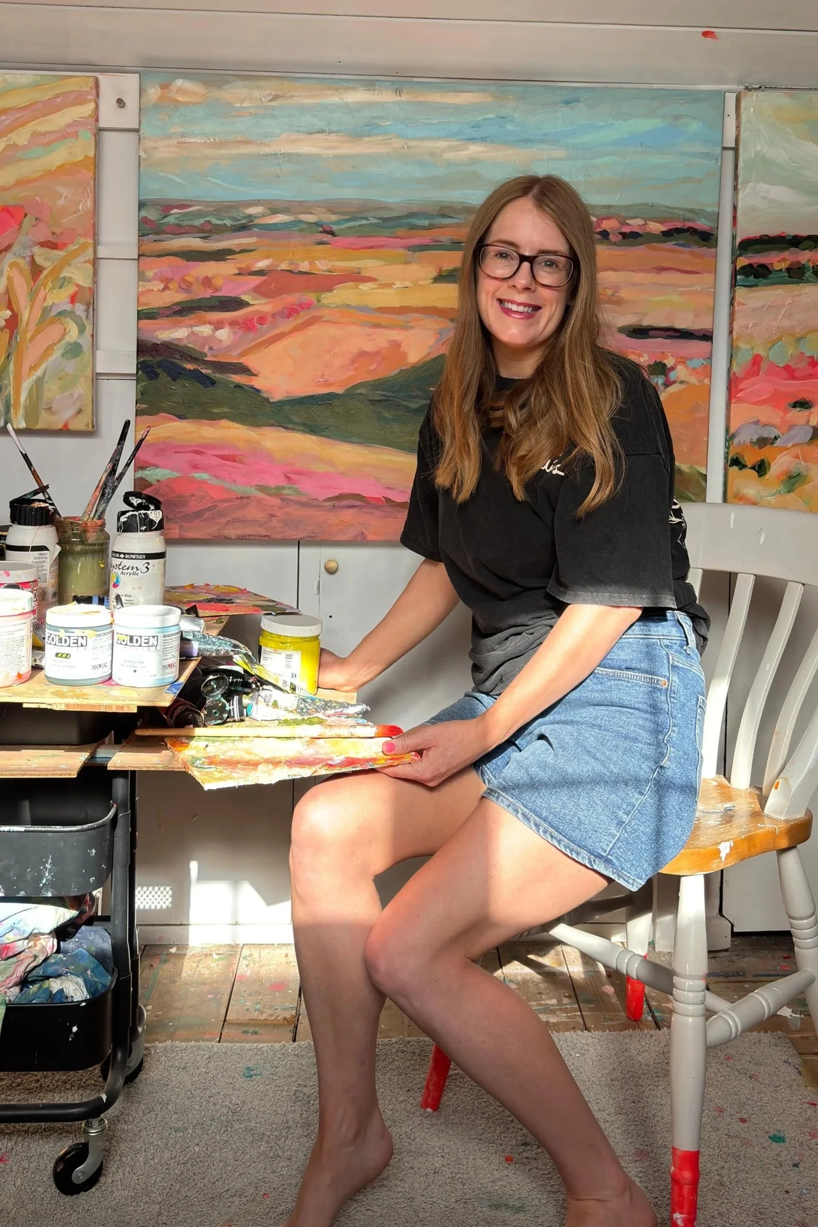 Contemporary British artist, Amy Rhodes in her studio with bright, colourful paintings