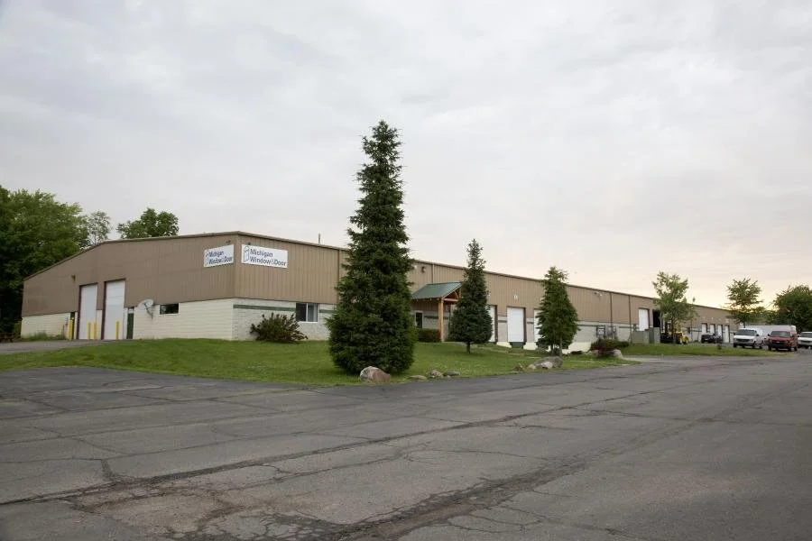 Single-storey industrial building at Zander Industrial Plaza with a paved lot and evergreen trees