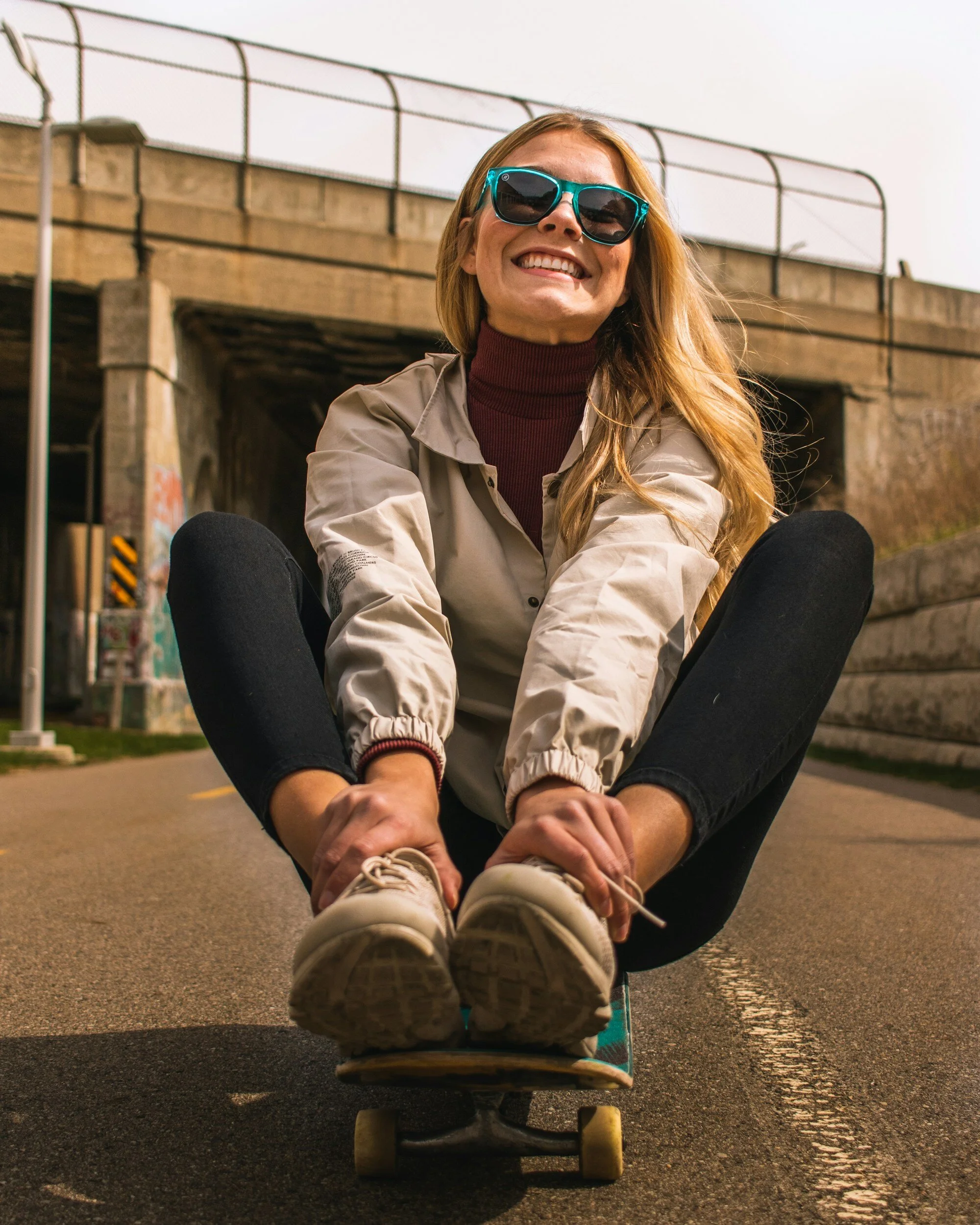 Woman smiling while skateboarding, representing joy, playfulness, and making time for activities that recharge your energy.