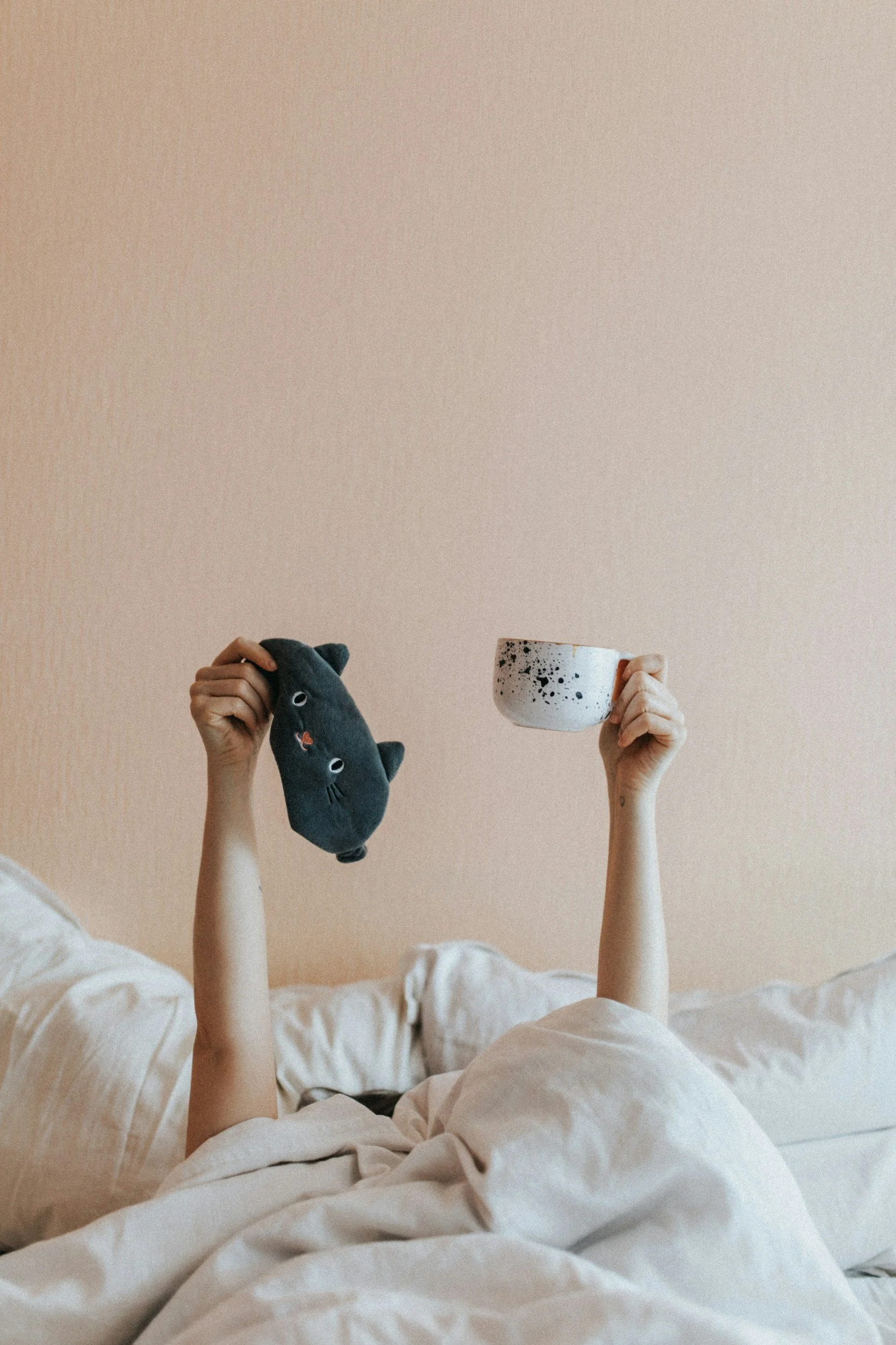 Person relaxing in bed with a cup of tea, representing restorative sleep and self-care.