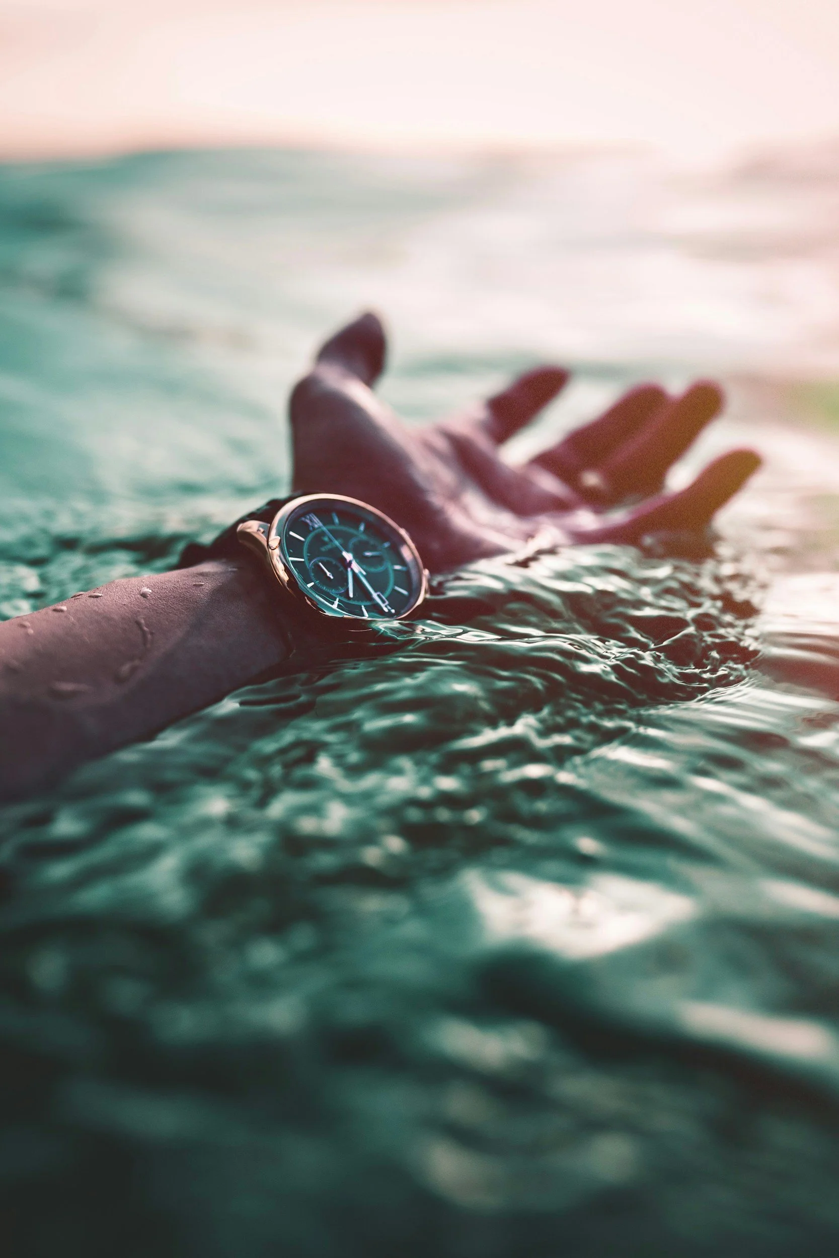Hand wearing a watch in the water, symbolizing saying no to protect your time, energy, and personal priorities.