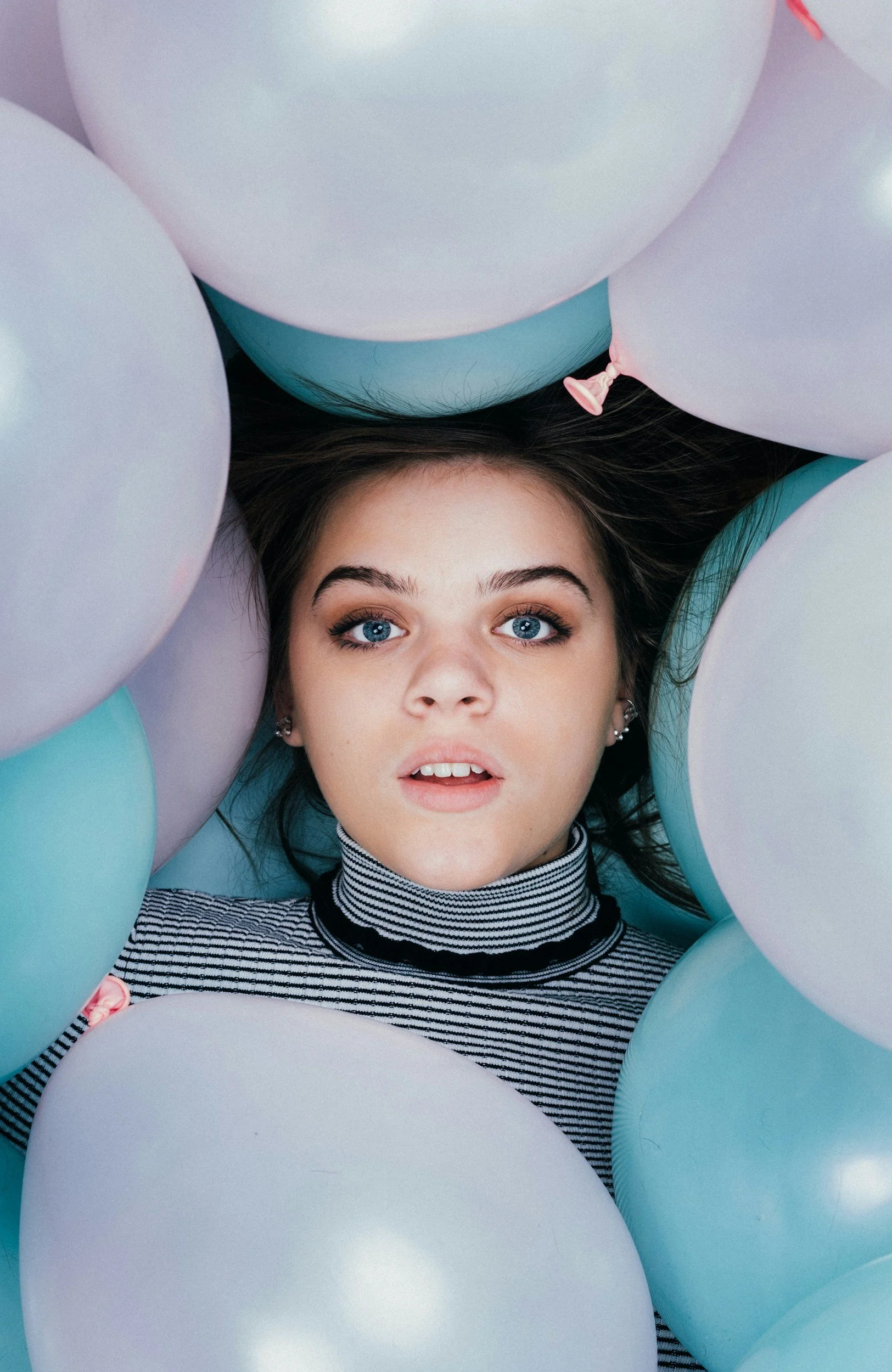 Young woman surrounded by balloons, representing staying present and avoiding old family patterns during the holidays.