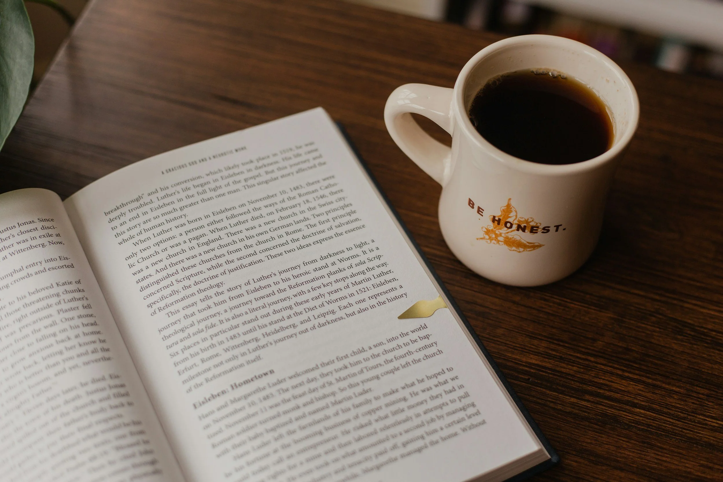 Open book and coffee on a table, symbolizing self-reflection, honest conversations, and personal growth.
