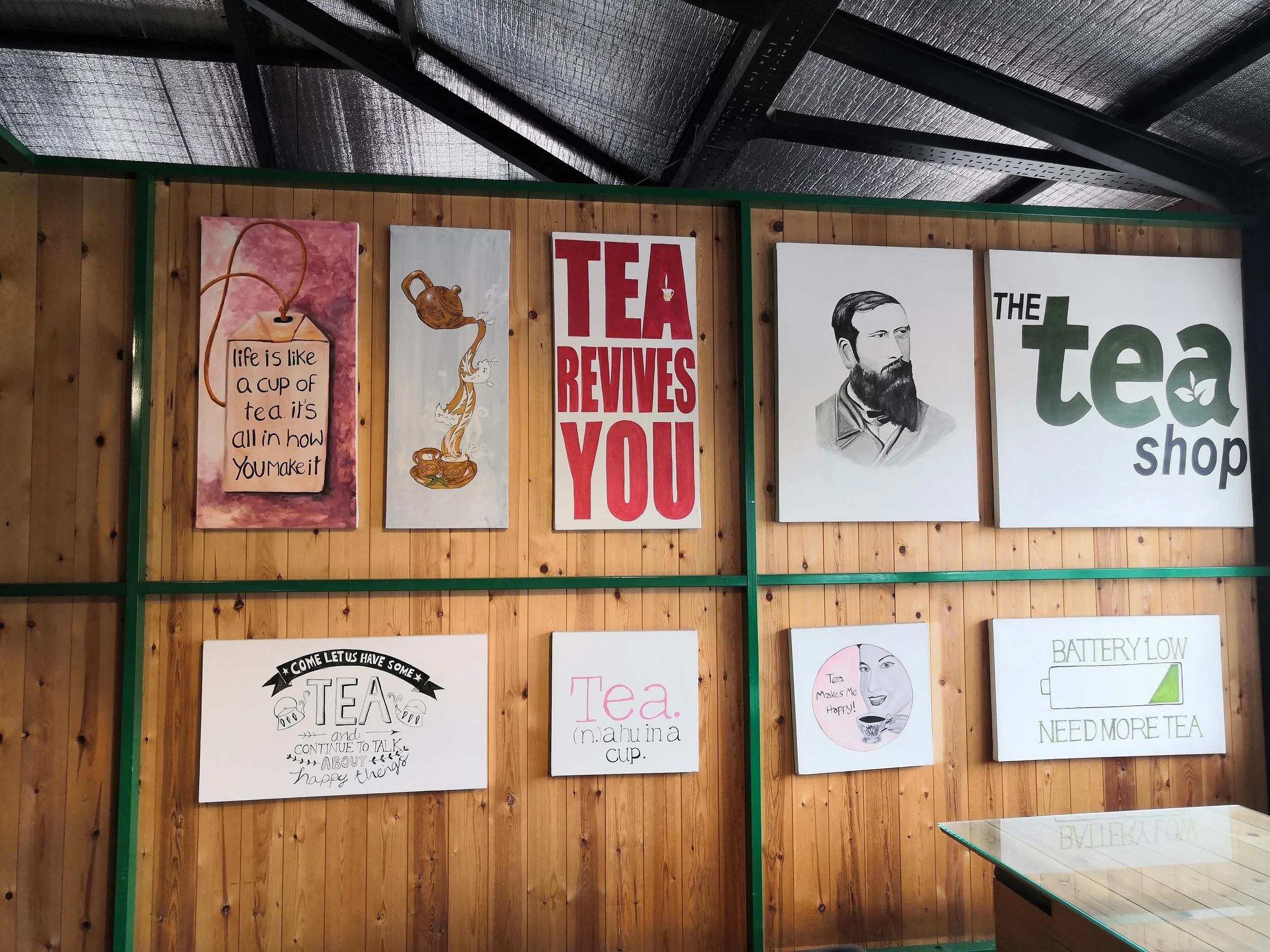 Tea shop interior with colorful tea-themed artwork and a quote about slowing down and appreciating your surroundings.
