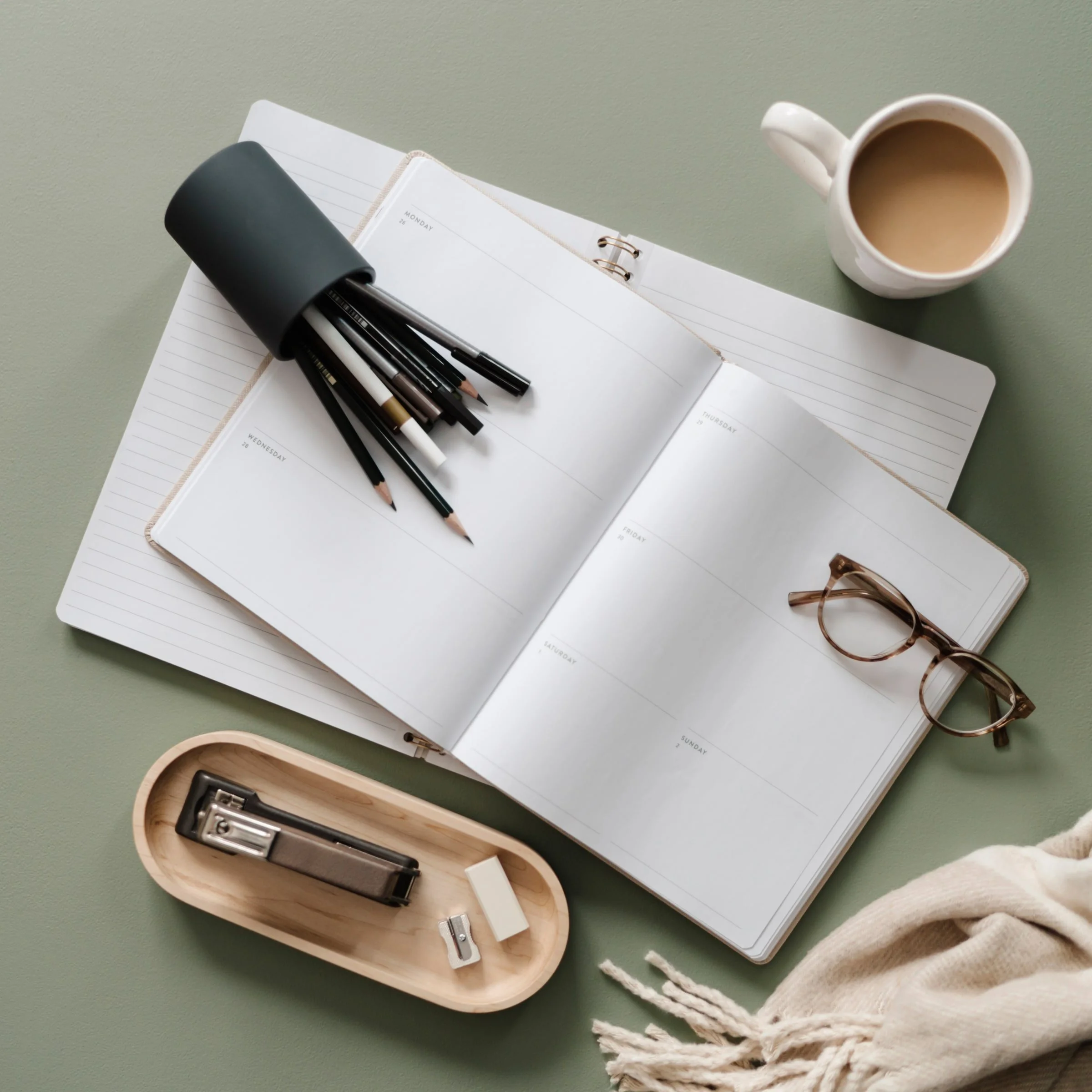 Open journal with pens, coffee, and glasses representing goal setting, self-reflection, and personal growth.