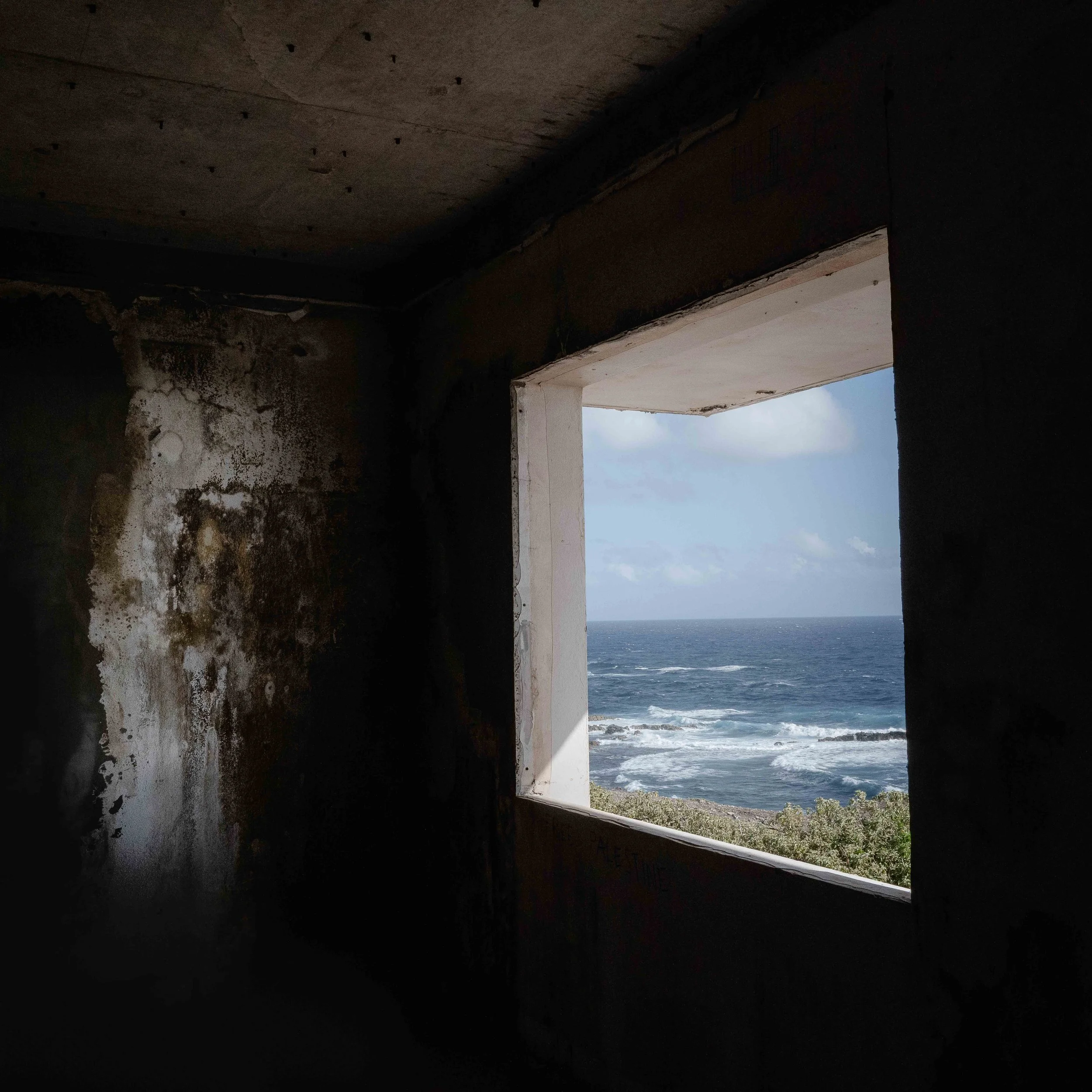 Photographie prise à la Désirade, révélant l'envers du décor paradisiaque entre stigmates du passé et présence humaine discrète. Photographie issue de la série "InDésirade" de Sophie Tournois, développée dans le cadre du mentorat photo en ligne de Pr