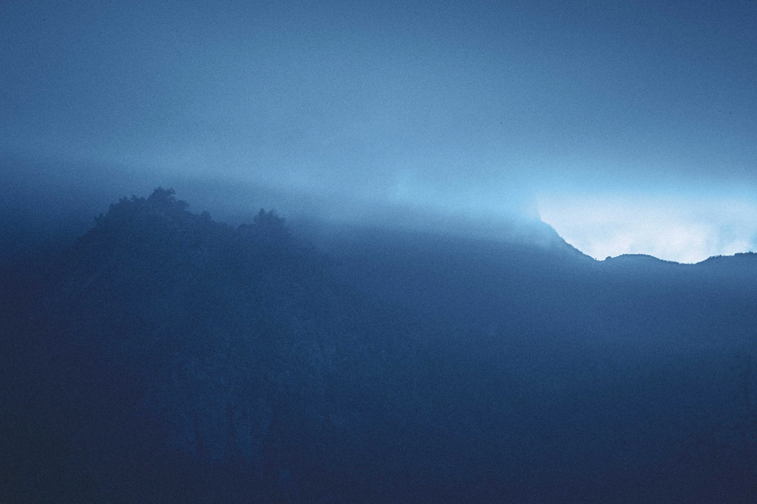 Paysage rocheux de l'île de Ua-Pou aux Marquises, baigné dans une lumière crépusculaire teintée de bleu. Photographie issue du projet "Retiens le bleu" d'Edwina Bellahouel, développé dans le cadre du mentorat photo en ligne de Préludes Photo.