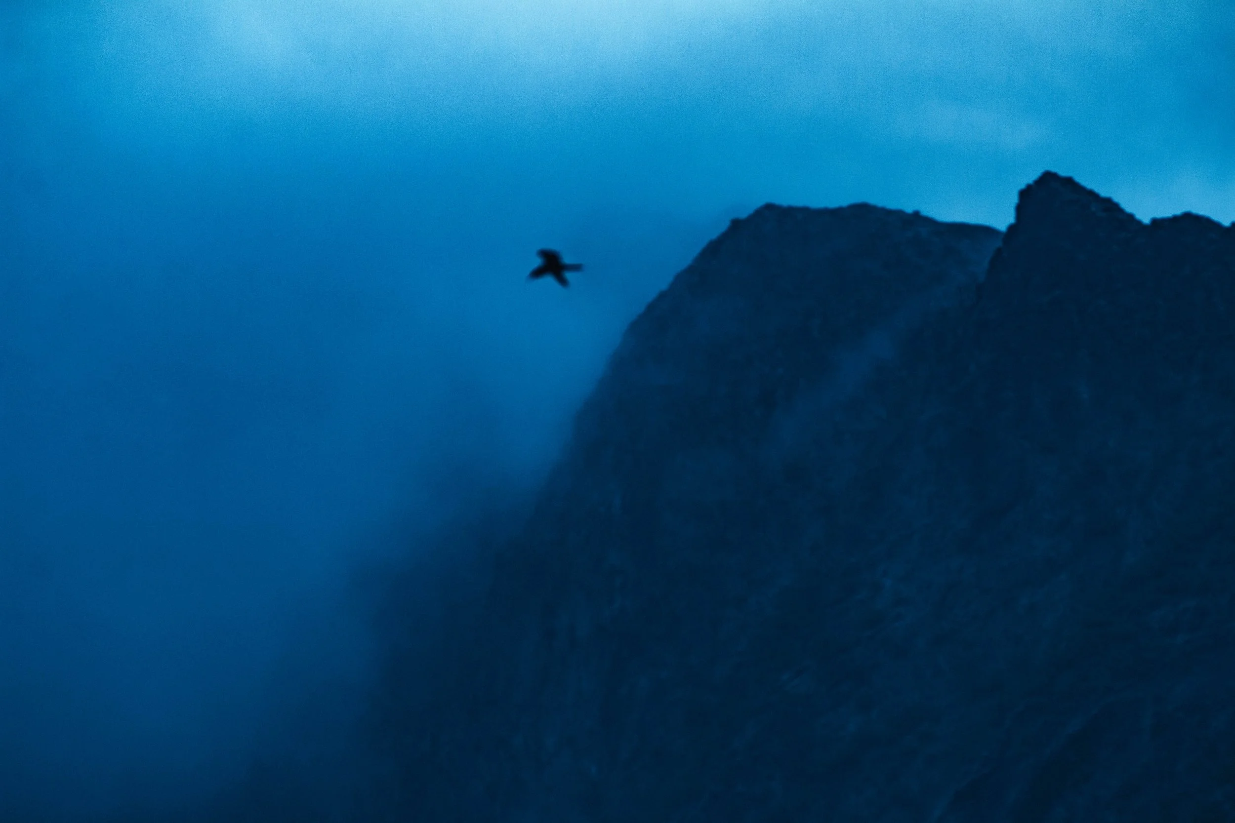 Paysage rocheux de l'île de Ua-Pou aux Marquises, baigné dans une lumière crépusculaire teintée de bleu. Photographie issue du projet "Retiens le bleu" d'Edwina Bellahouel, développé dans le cadre du mentorat photo en ligne de Préludes Photo.