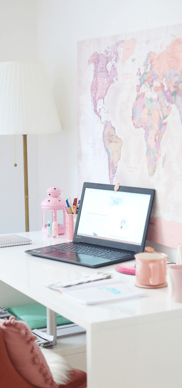 laptop on white desk with map on the wall
