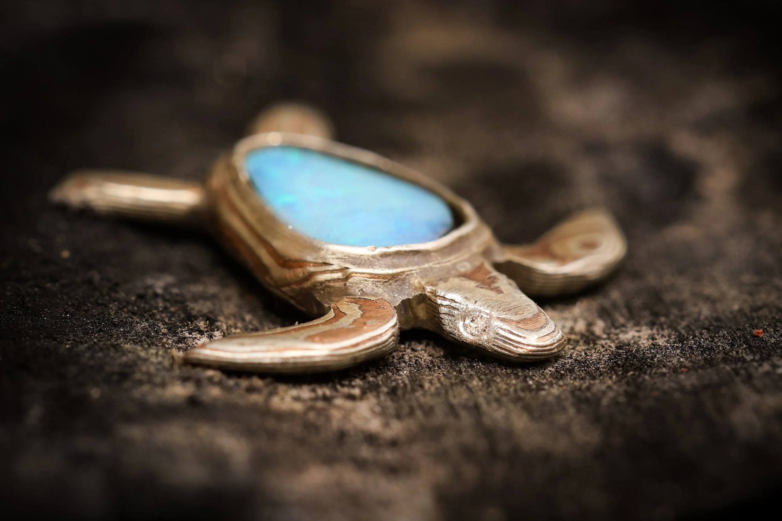 A piece of silver jewelry with a blue gemstone on dark textured background.