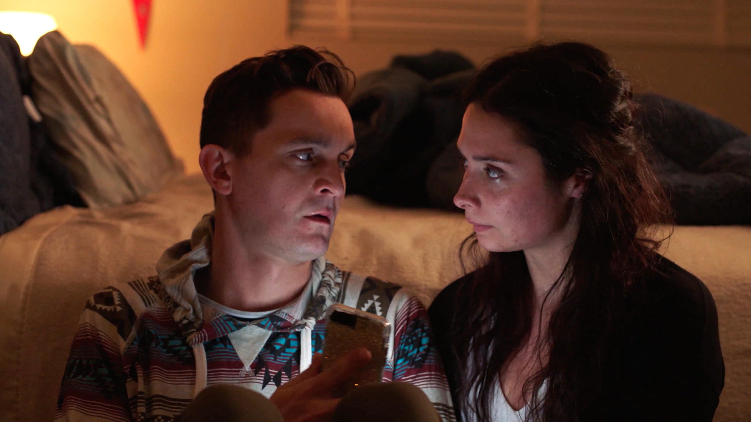 Young man and young woman sitting next to each other looking at a phone
