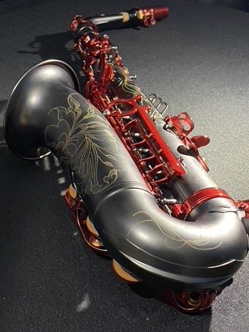 A custom red and black acoustic saxophone with gold detailing.