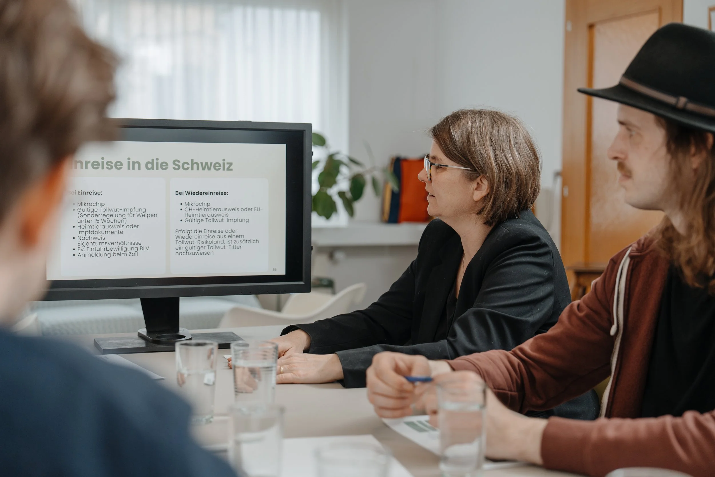 Kursteilnehmende des Theoriekurses, während eine Frau auf einem Bildschirm Informationen über Reisen in die Schweiz mit Hund liest.