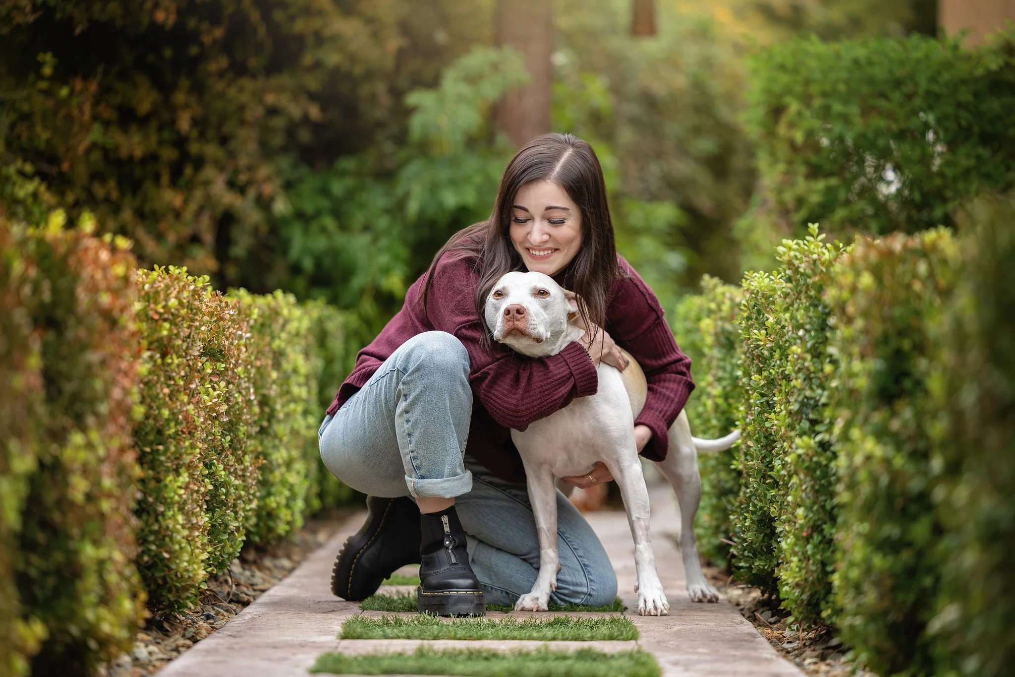 girl hugging her white pitbull in her backyard