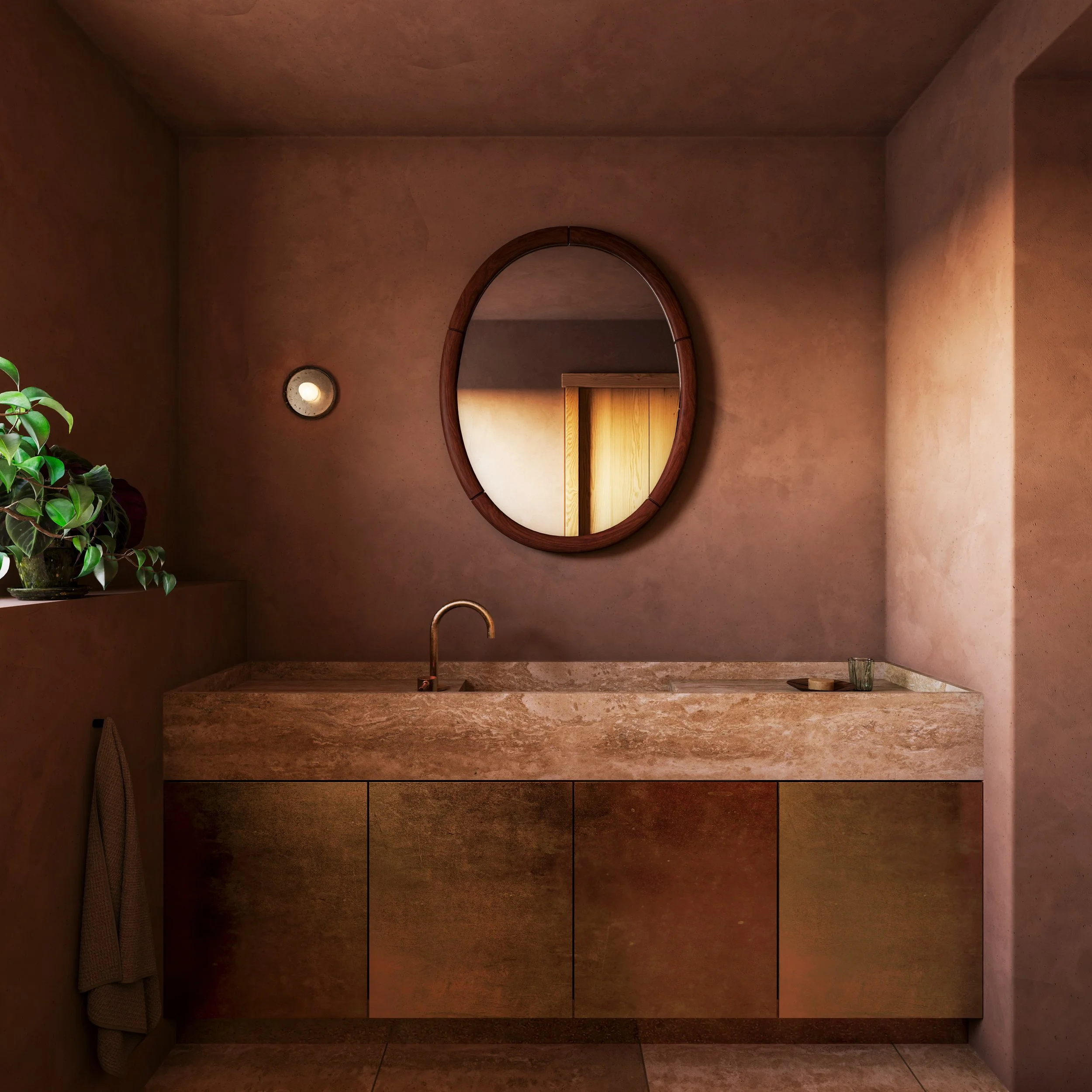 Minimalist bathroom vanity with a rounded rectangular sink, a gold faucet, a wooden cabinet, a round mirror, a small light, and a plant on the left.