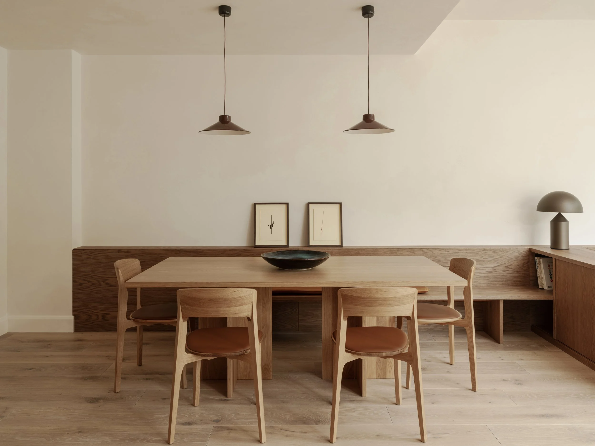 A six person oak dining table is surrounded by four chairs and a bench on the side facing the wall.