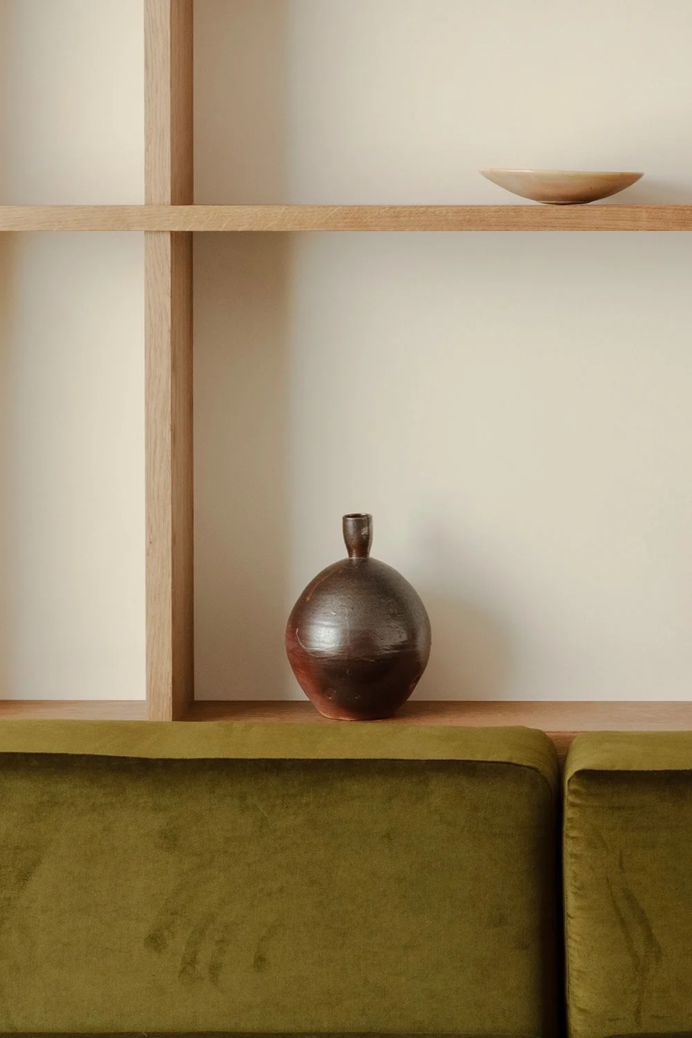 bespoke oak open plan shelving with brown ceramic vase and green velvet sofa cushion