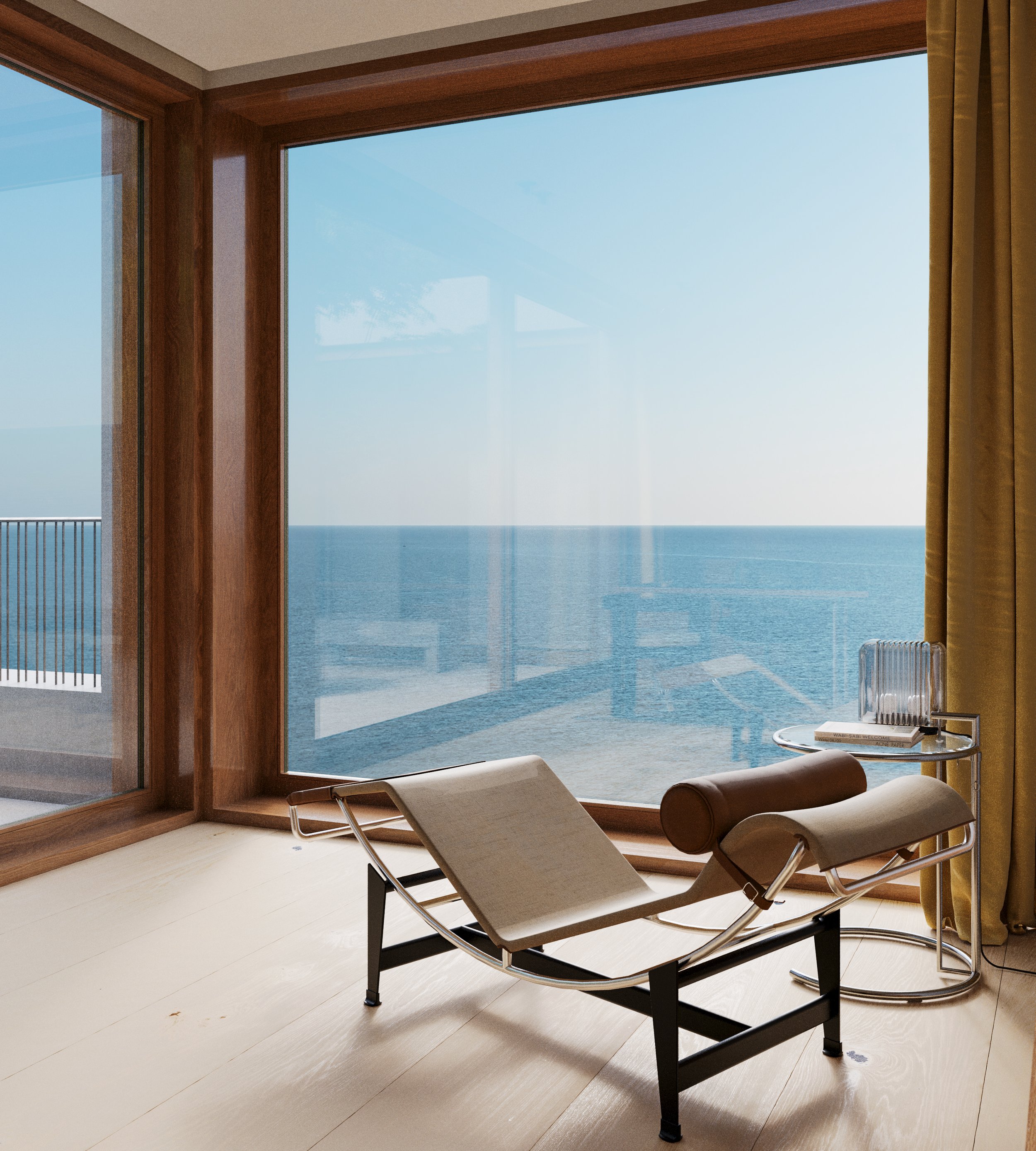 Living room with large window overlooking the ocean, modern lounge chair, side table with books and decorative object, and gold curtains.