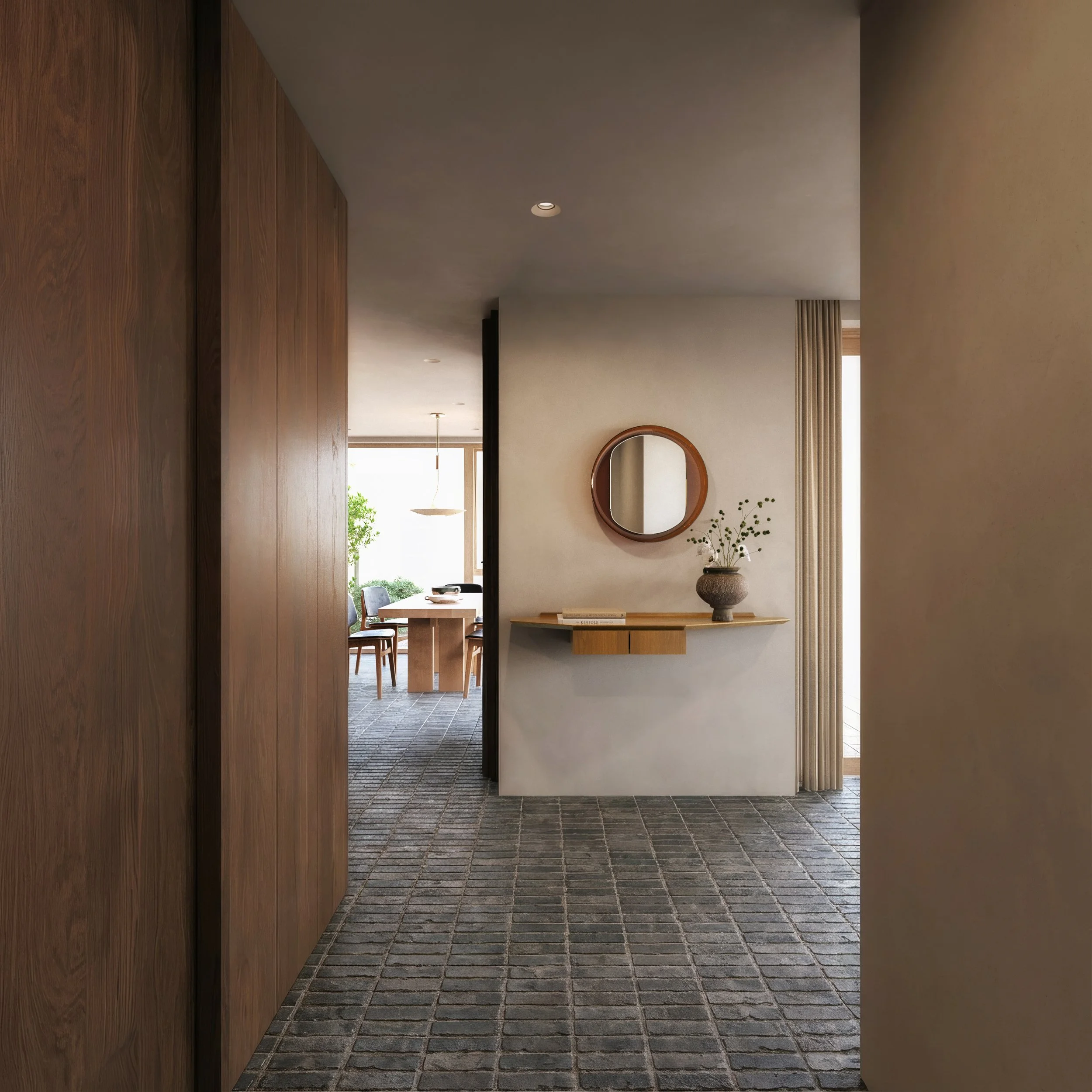 Interior view of a modern home hallway with wooden and beige walls, a mosaic tile floor, a circular mirror above a wooden console table, and a decorative vase with greenery.