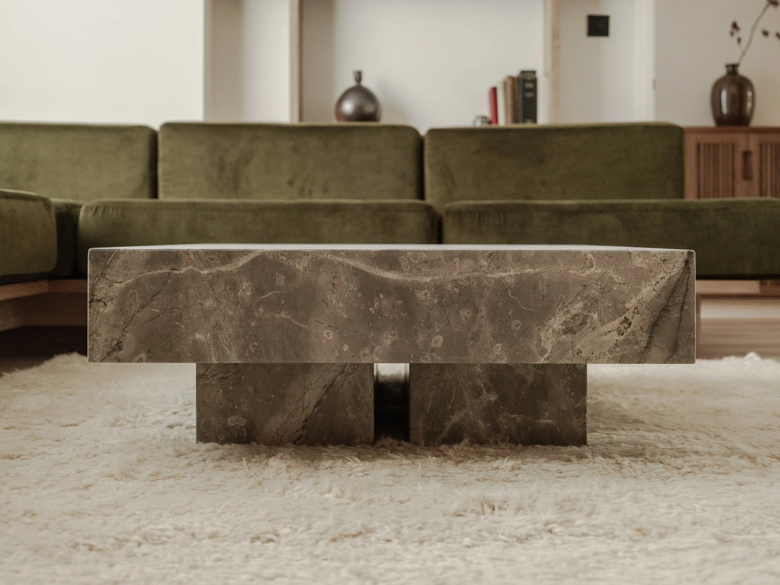 bespoke coffee table in grey fior di bosco marble  with cream high pile rug and green velvet bespoke sofa