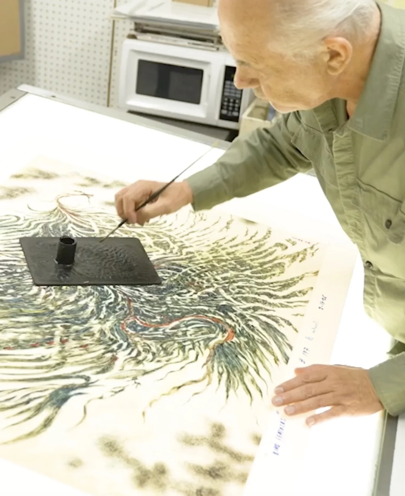 Kolibri's master printer hand-finishing a serigraph layer over a giclée base.