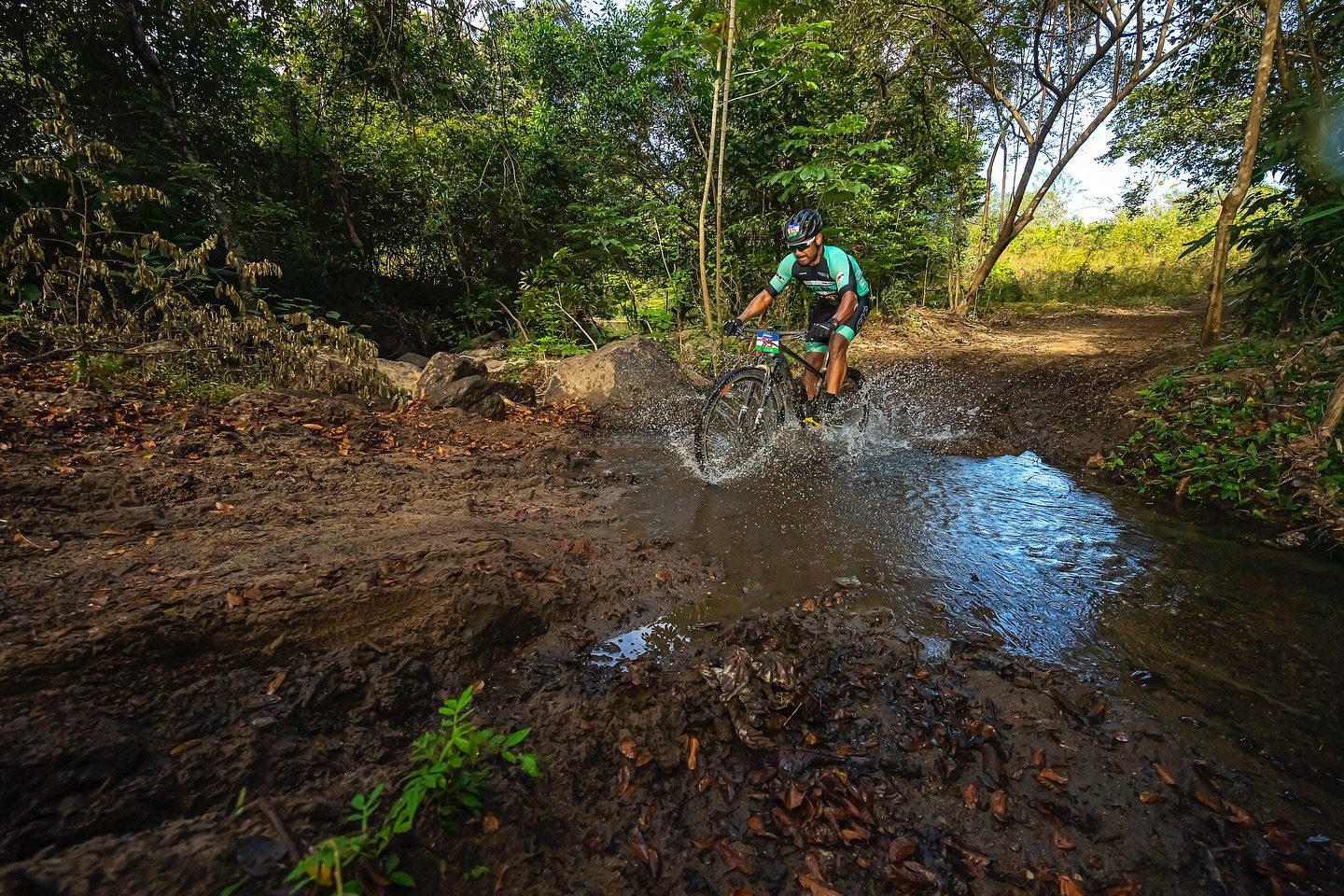 Mountain biker rips through a puddle at Rincon trails Costa Rica.