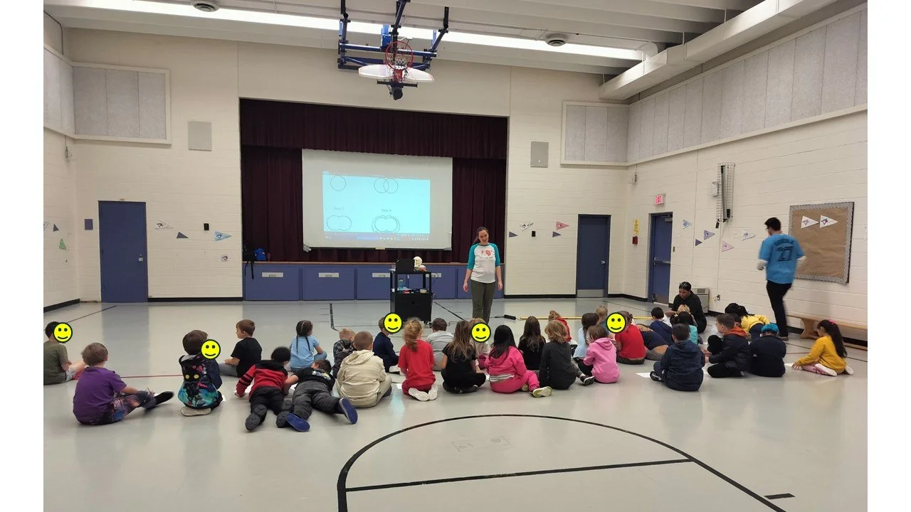 Author Jenny Mouse teaching students in a gym how to draw a brain